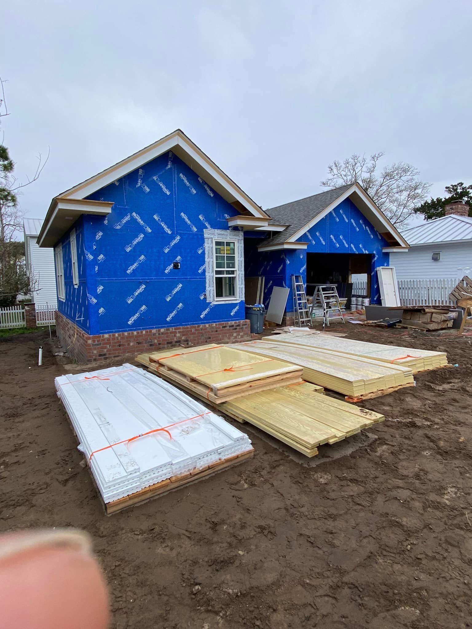 A house is being built with a lot of wood in front of it.