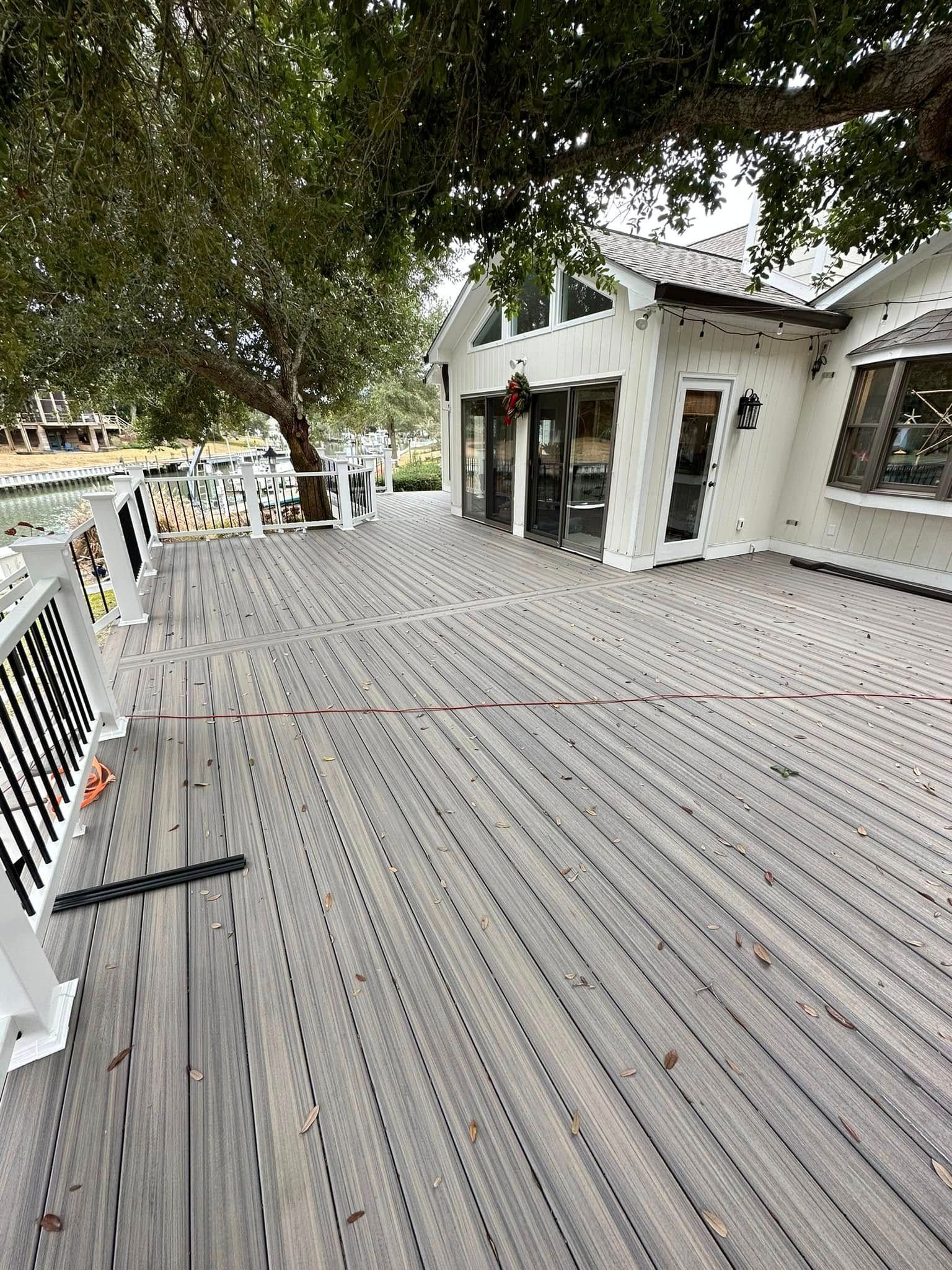 A large wooden deck with a white building in the background.