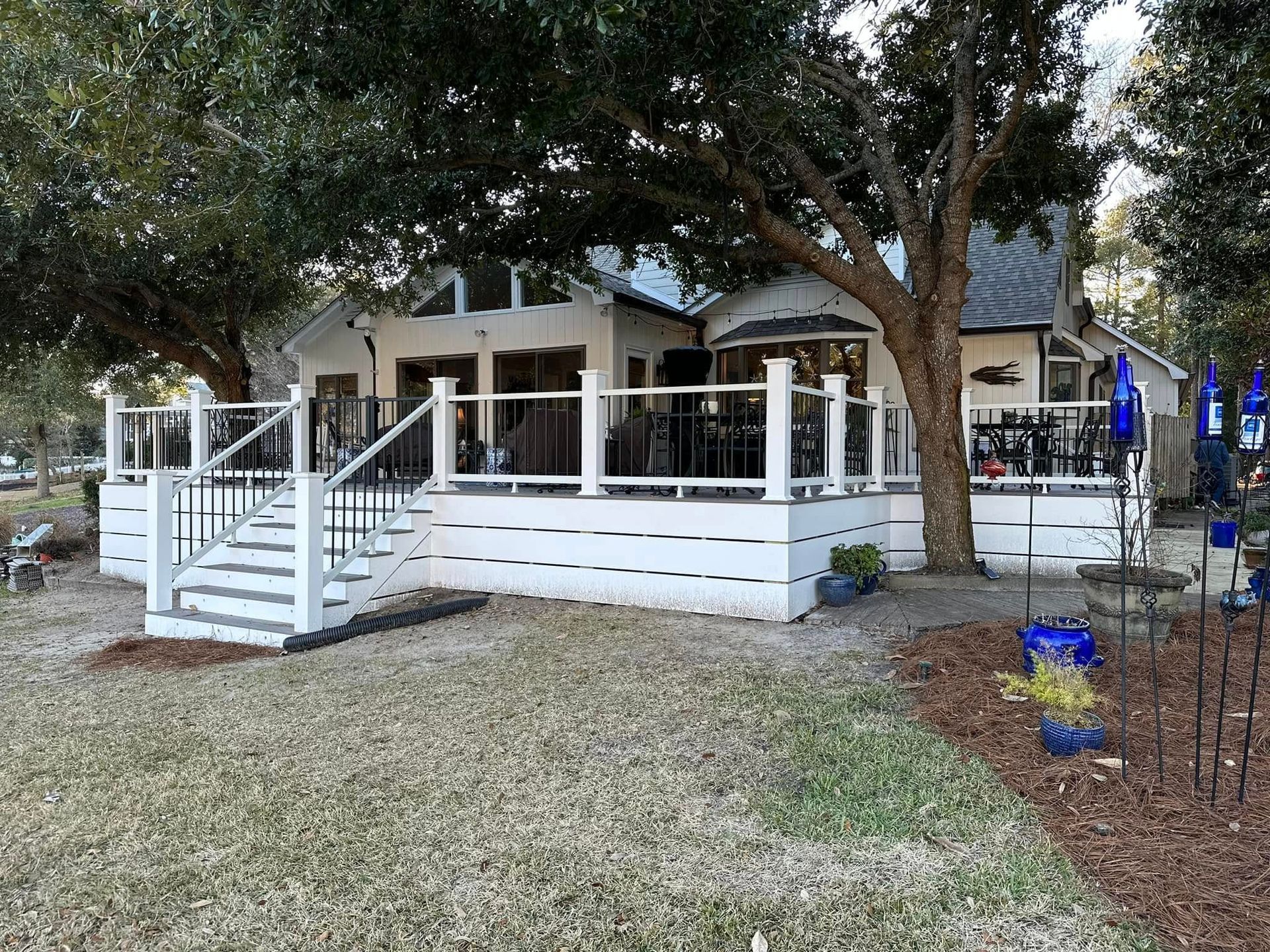 A white house with a large deck and stairs in front of it.