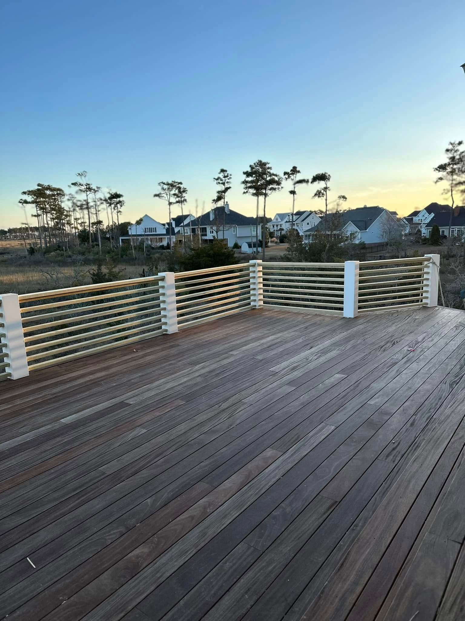 A wooden deck with a fence and houses in the background