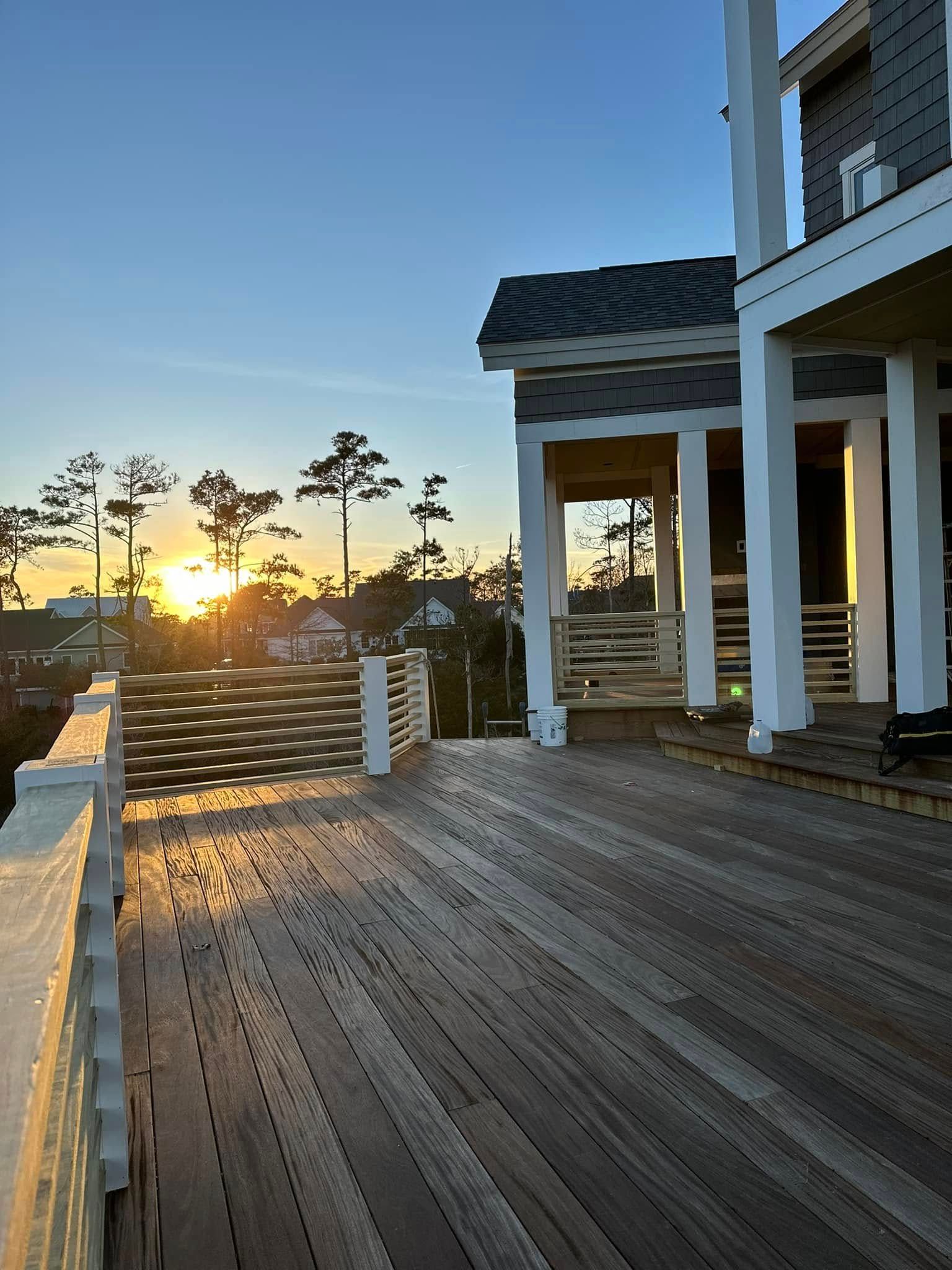 A large house with a wooden deck and a sunset in the background.