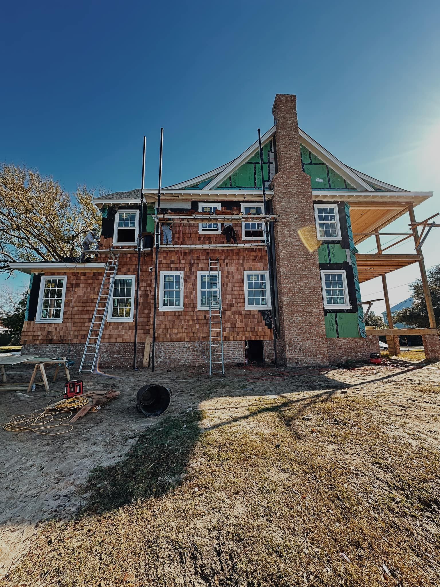 A large brick house is being built in a field.