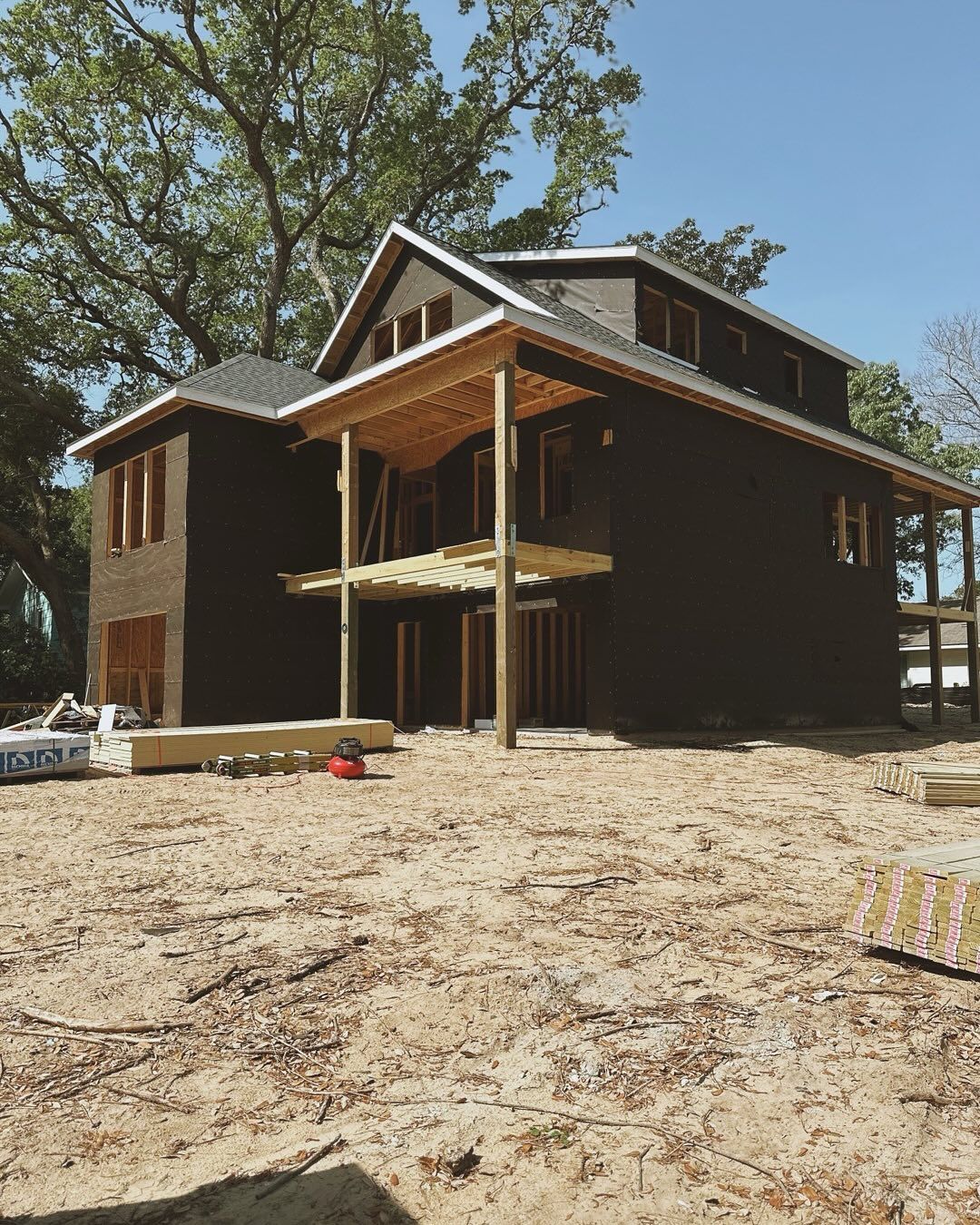 A large house is being built in the middle of a dirt field