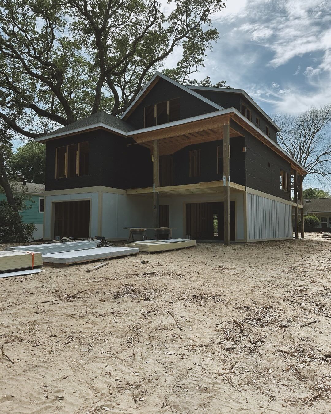 A large house is being built in the middle of a dirt field.