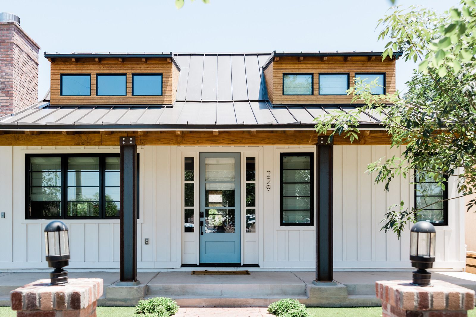 A white house with a blue door and a metal roof.