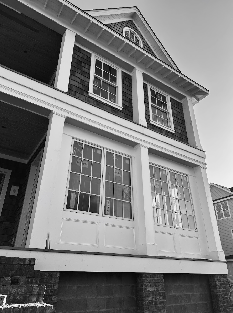 Two-story house with white trim, dark siding, and multiple windows.