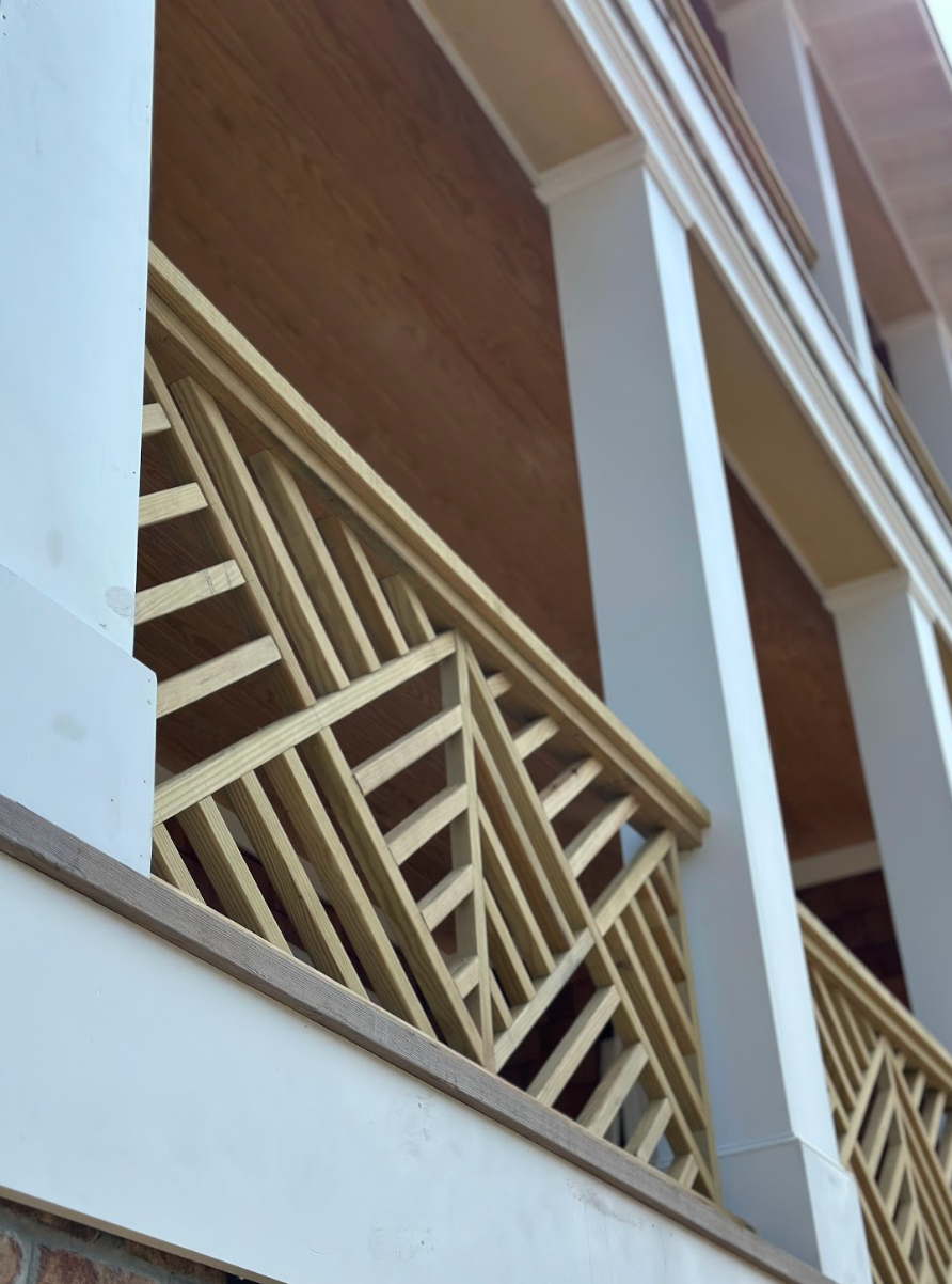 Cream and beige building with geometric wooden balcony railing.