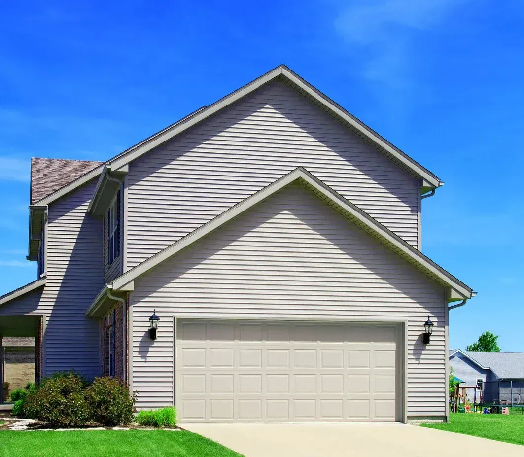 A house with a garage door and a blue sky in the background.