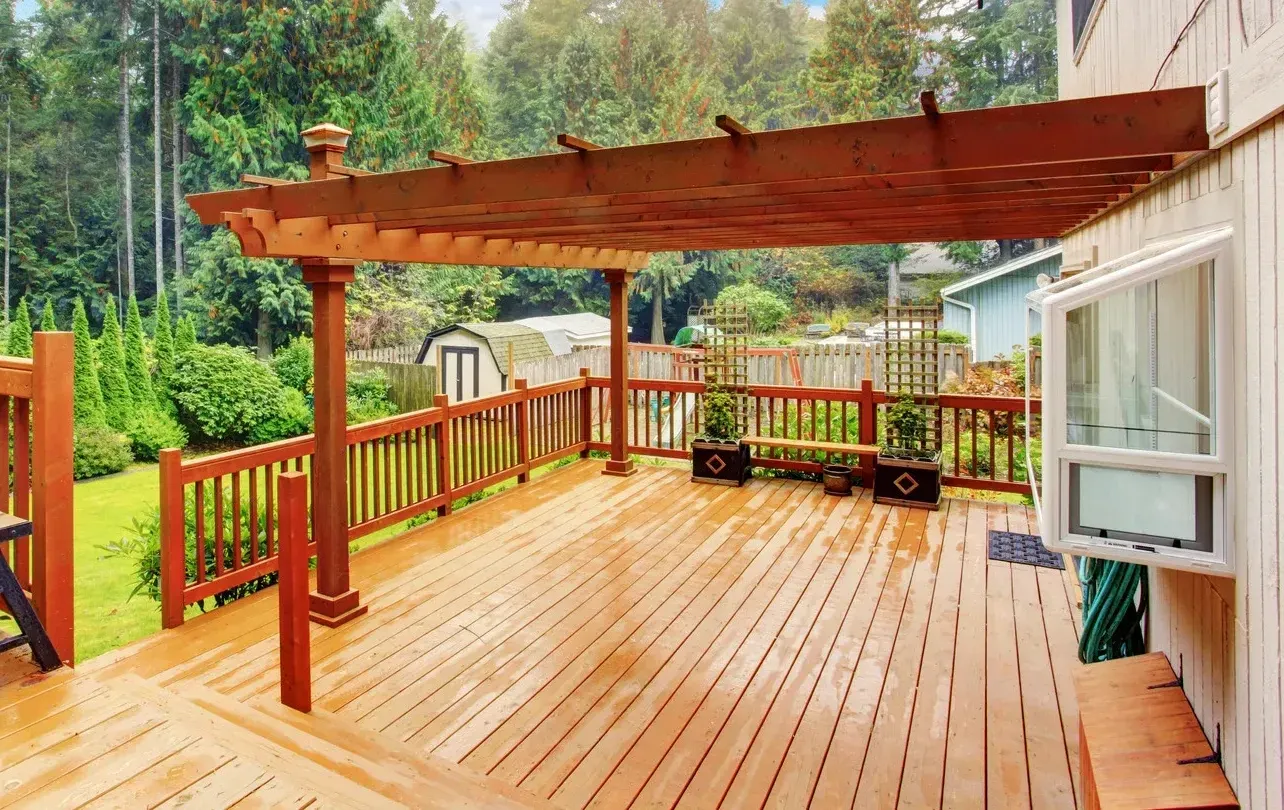 A large wooden deck with a pergola on top of it.
