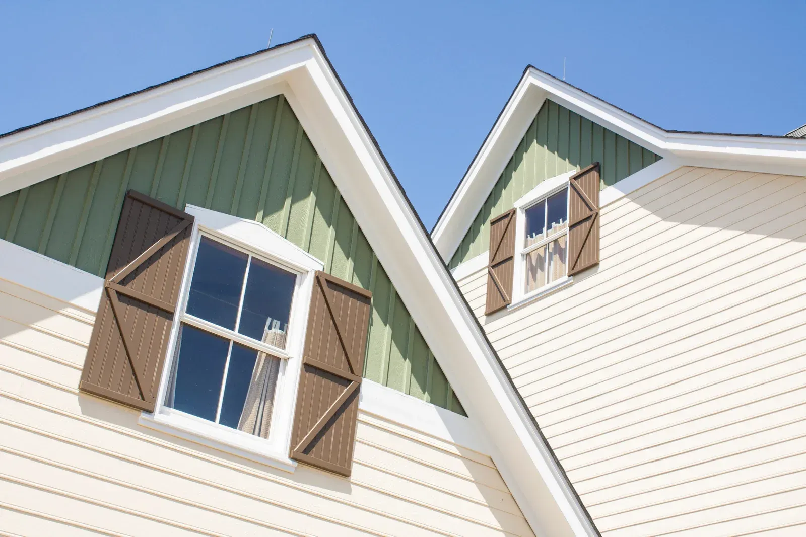 A house with a green roof and brown shutters on the windows.