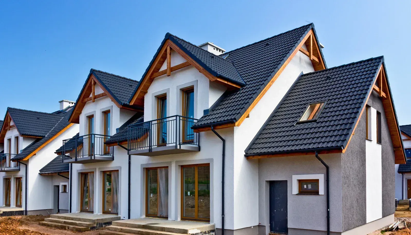 A white house with a black roof and balconies