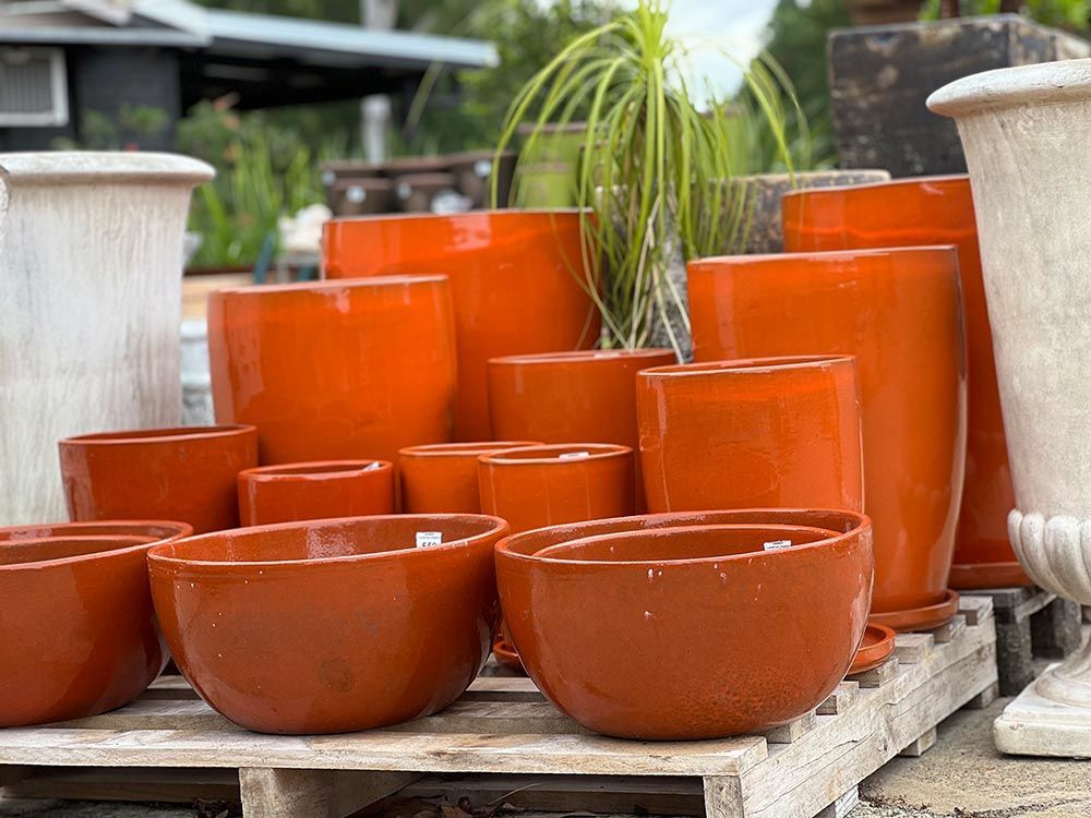 A Bunch Of Orange Pots Are Sitting On A Wooden Pallet — Cooroy Landscape Supplies and Garden Centre in Eumundi, QLD