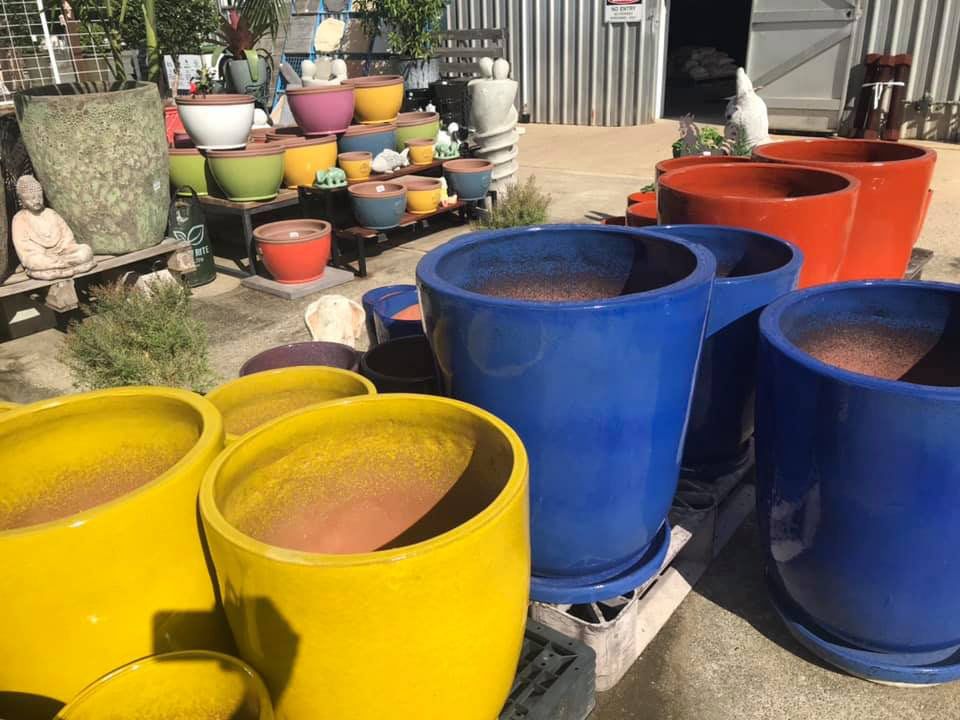 A Bunch Of Colorful Pots Are Sitting On Top Of A Pallet — Cooroy Landscape Supplies and Garden Centre in Gympie, QLD