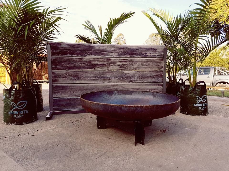 A Large Fire Pit Is Sitting In Front Of A Wooden Wall — Cooroy Landscape Supplies and Garden Centre in Gympie, QLD