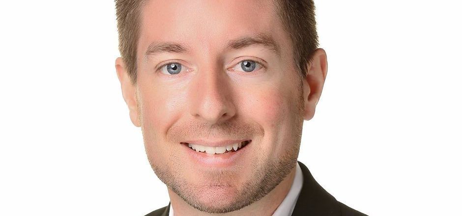 A man in a suit and tie is smiling for the camera.