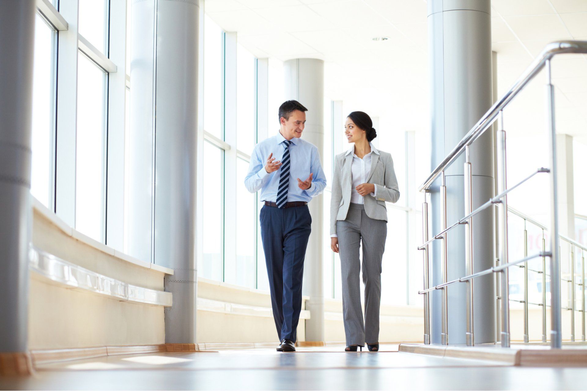 Two business people walking and talking down a hallway