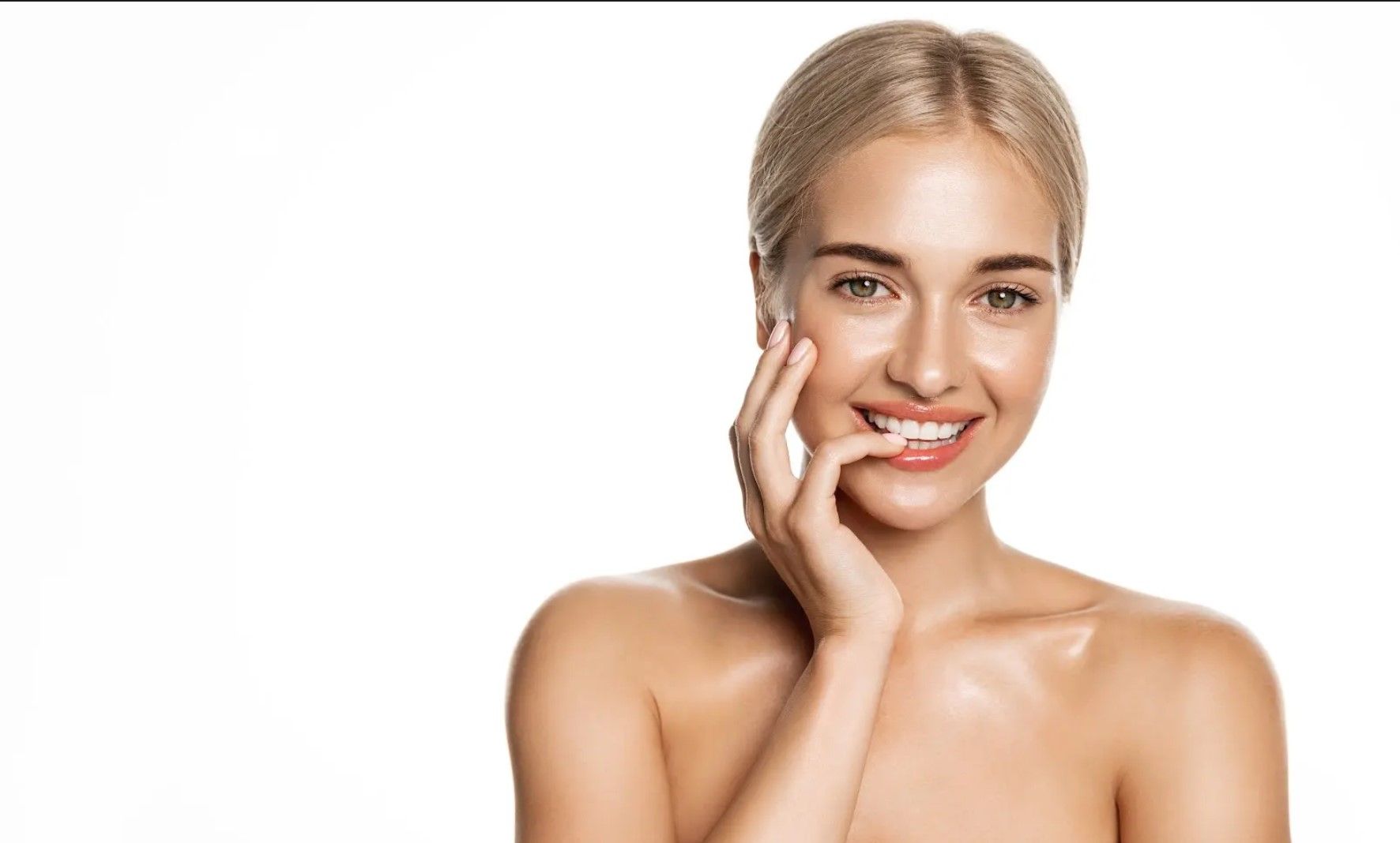 A woman is touching her face with her hand and smiling.