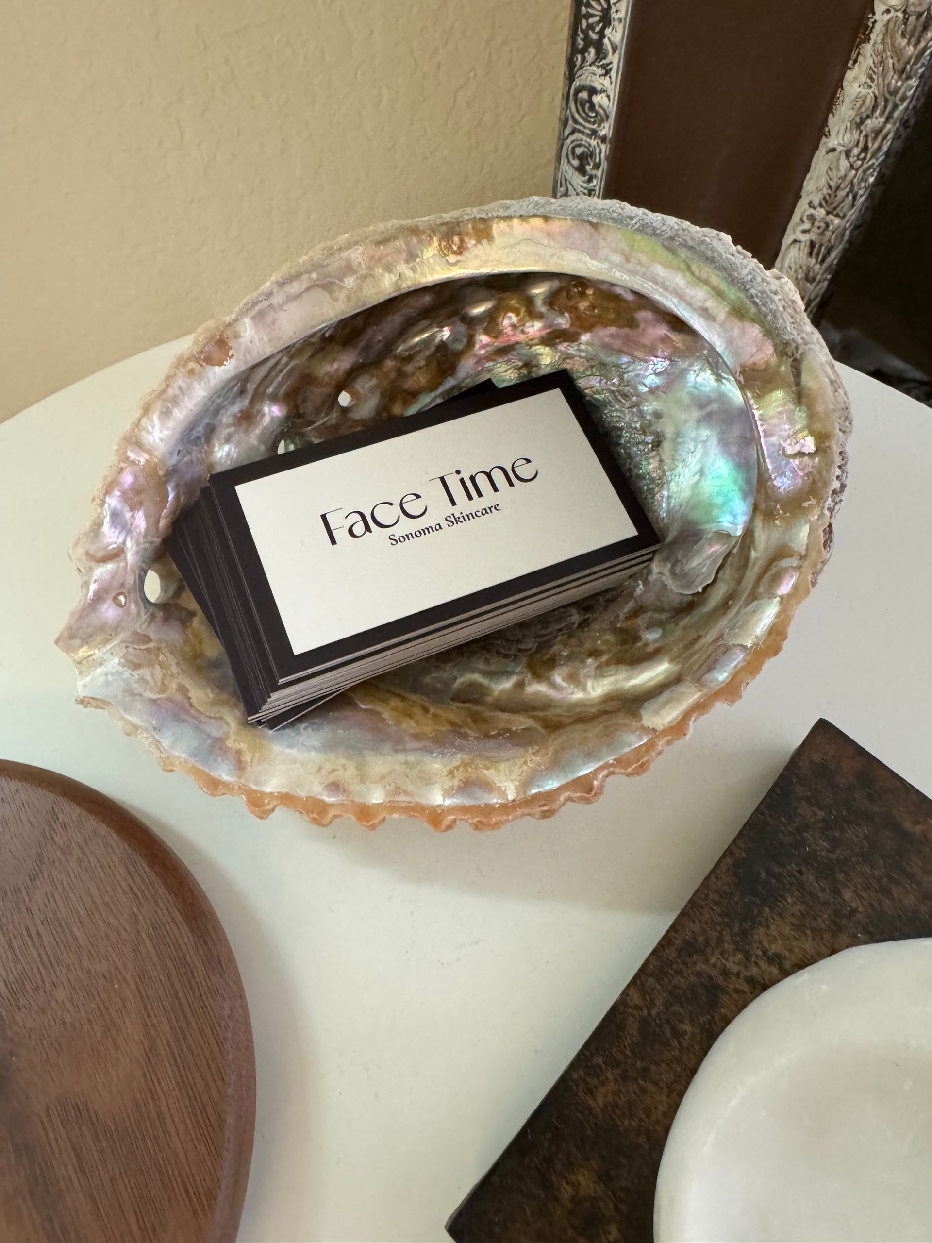 A business card is sitting in a shell on a table