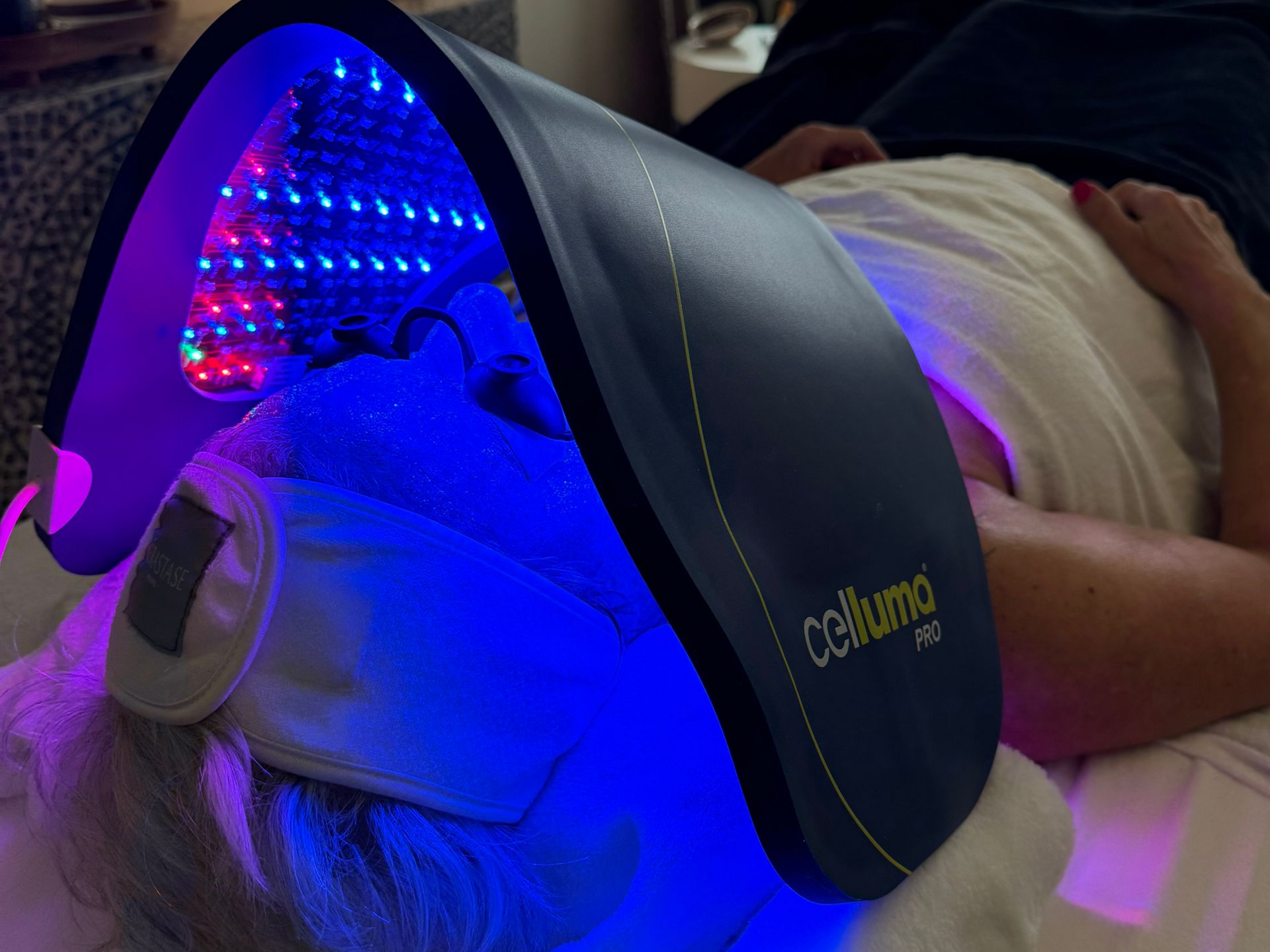 Woman receiving LED light therapy from a technician in a medical spa setting.