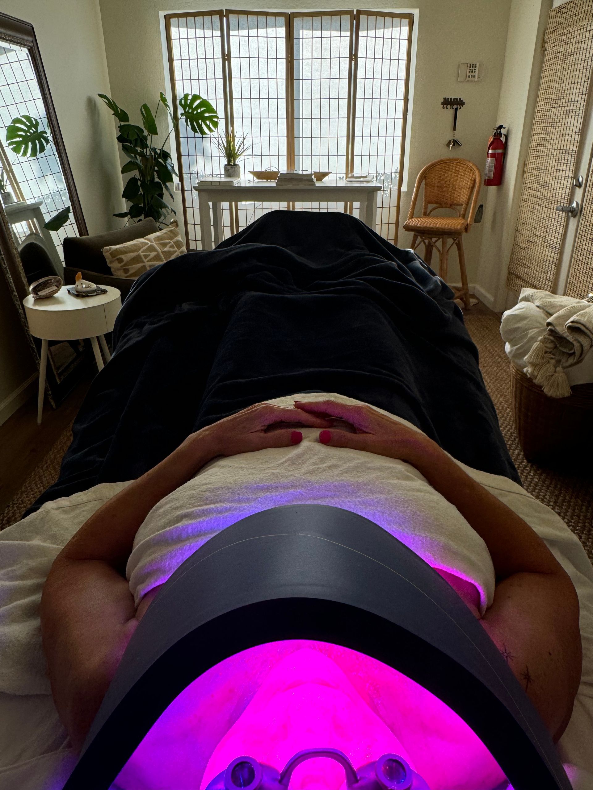 A woman is laying on a bed with a purple light on her face.