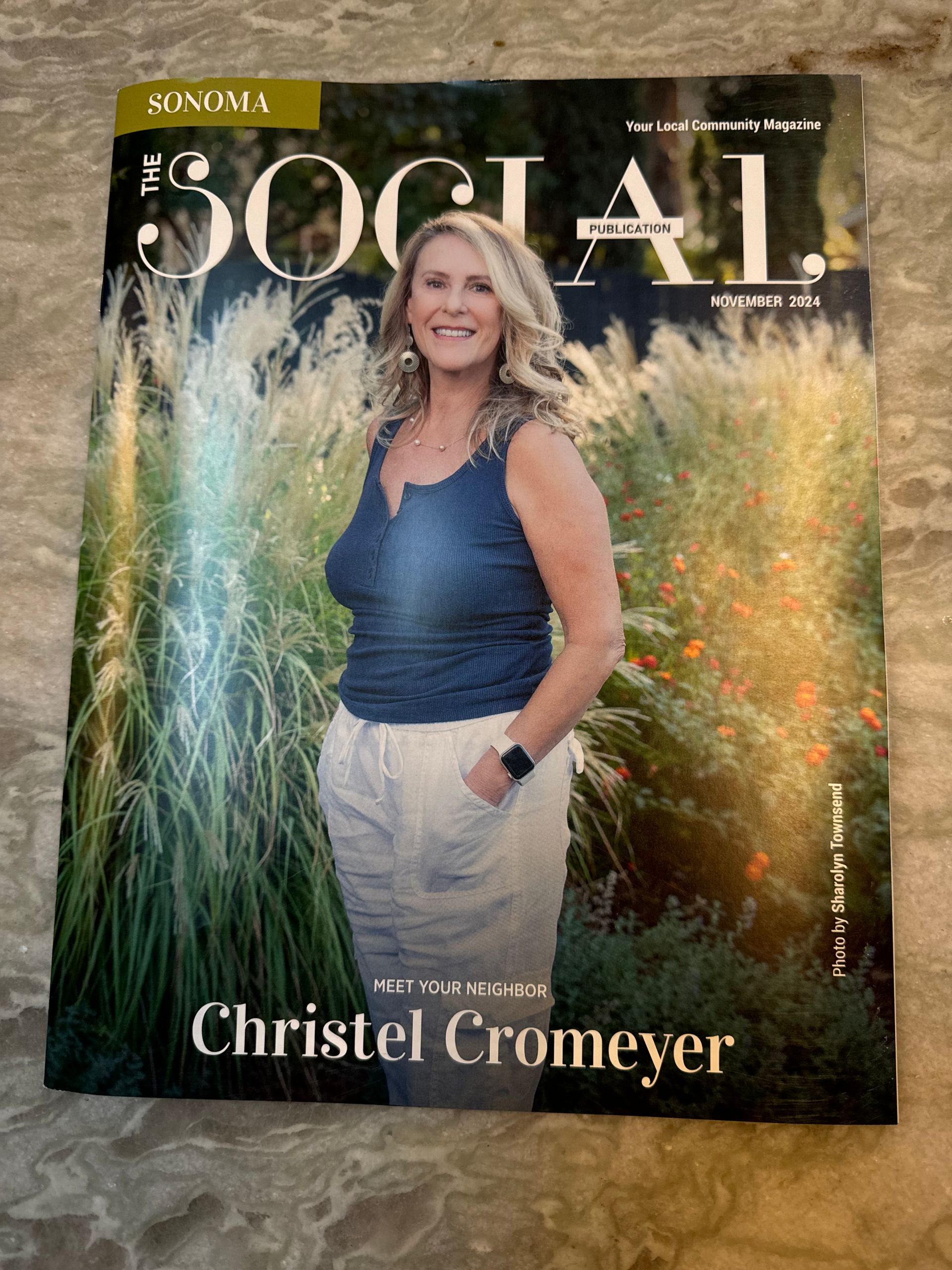 A woman is standing in front of tall grass on the cover of a magazine.