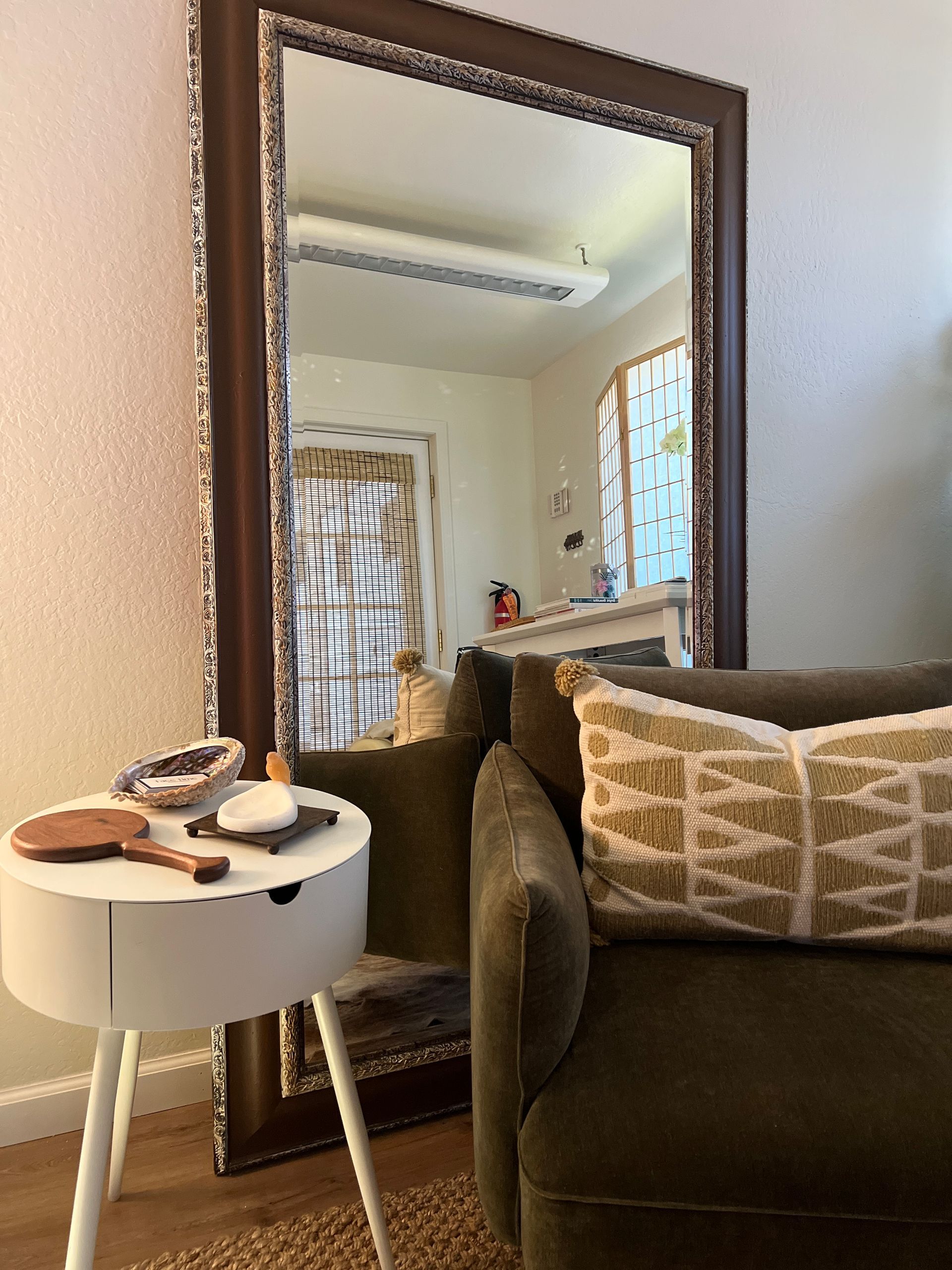 A living room with a large mirror and a chair.