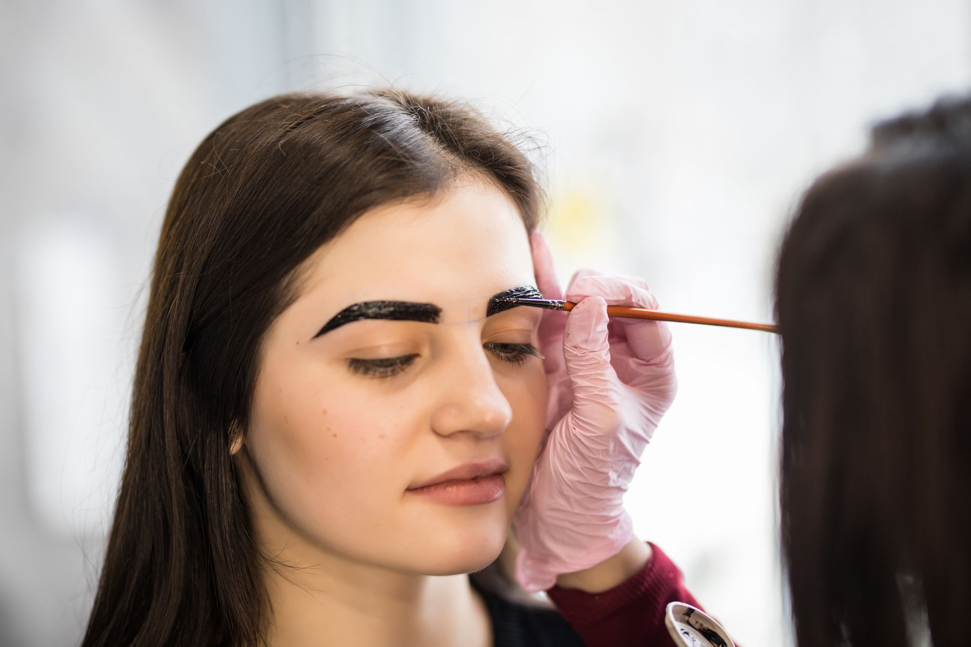 A woman is getting her eyebrows dyed in a salon.