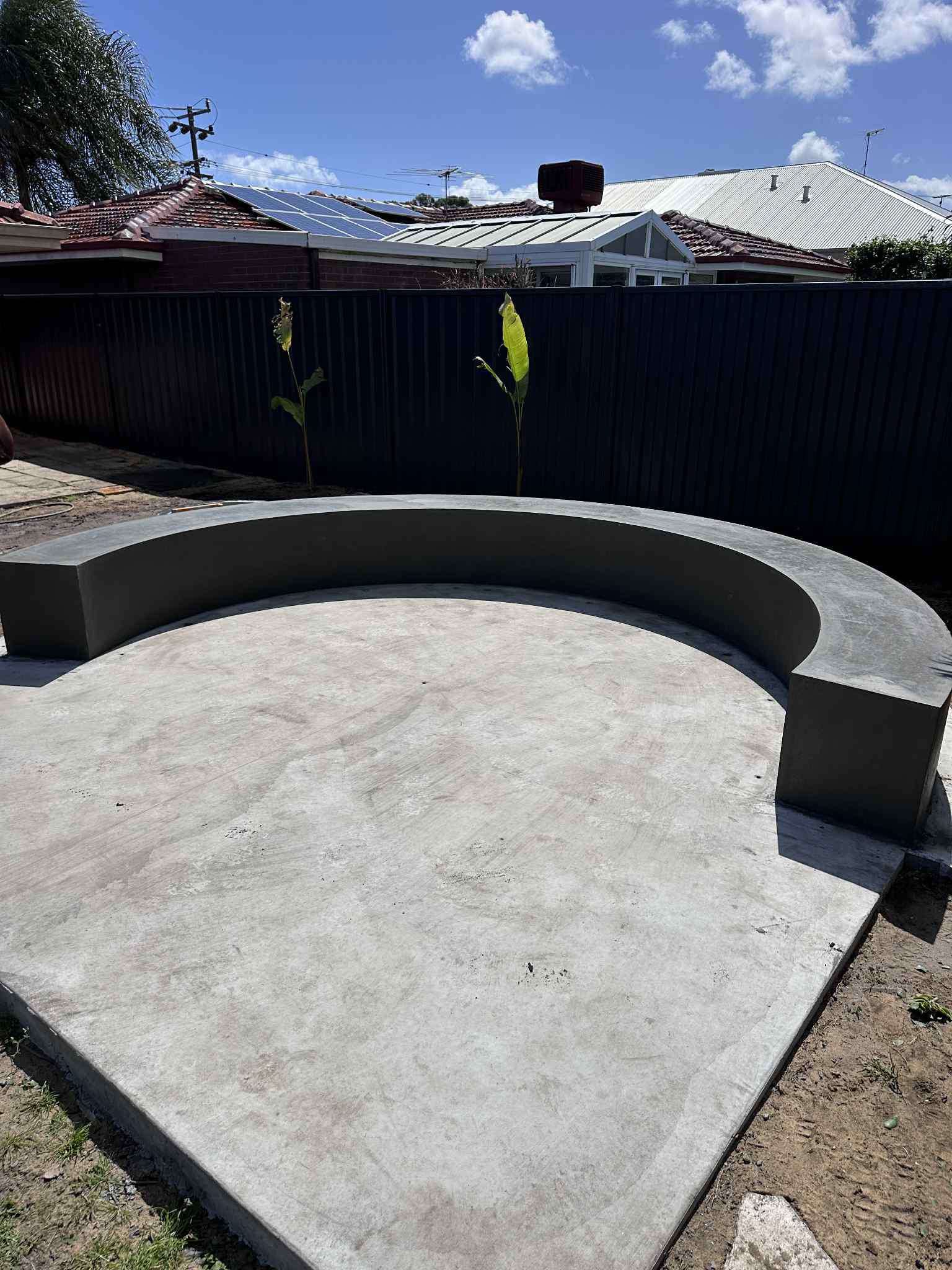 Architectural concrete curved bench seat for fireplace in backyard of home
