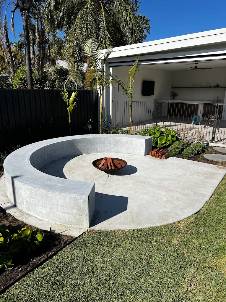Outdoor architectural circular concrete bench seat and fireplace concrete slab in backyard of home