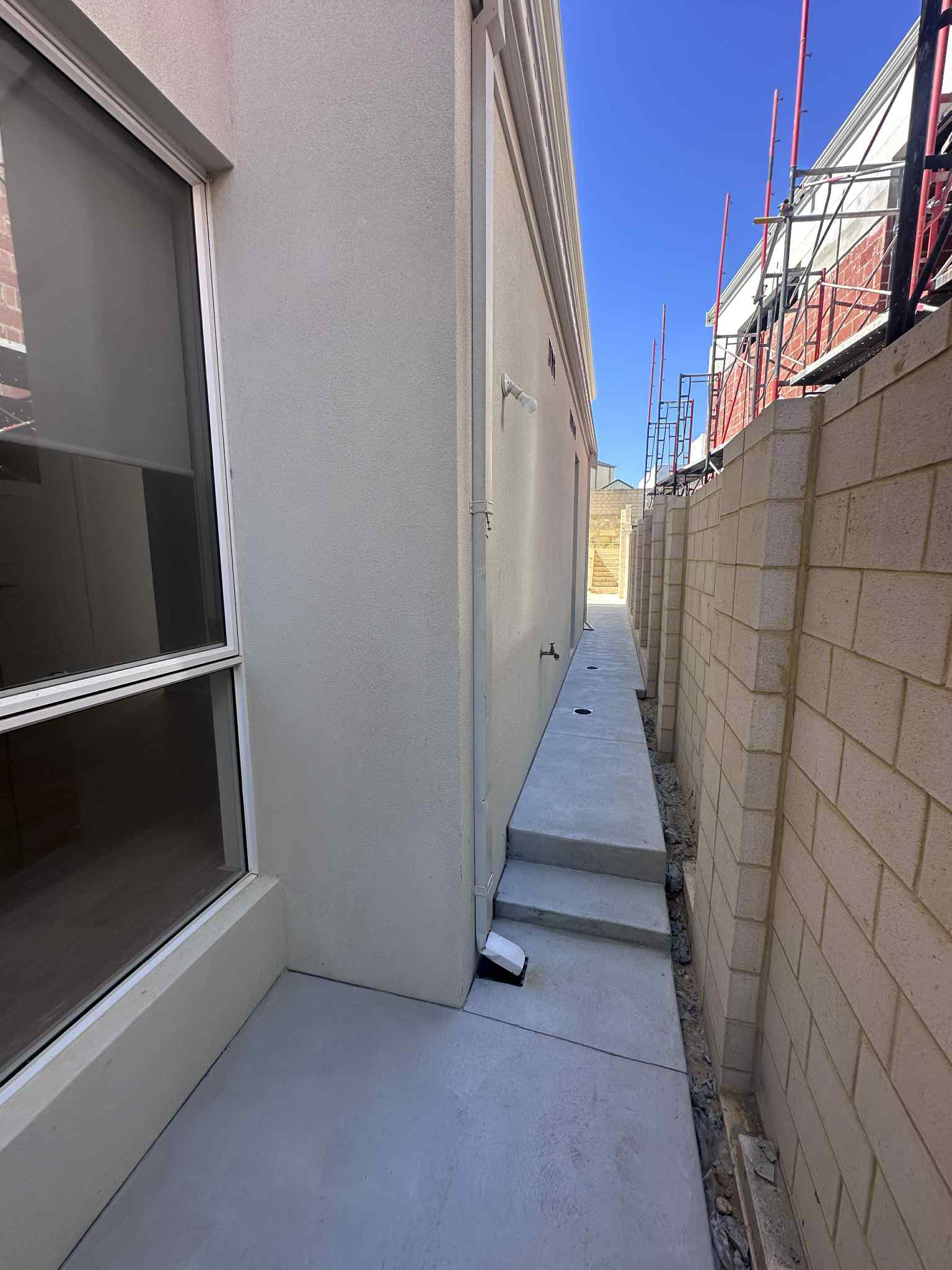 Grey concrete path with steps down to side access of home. 