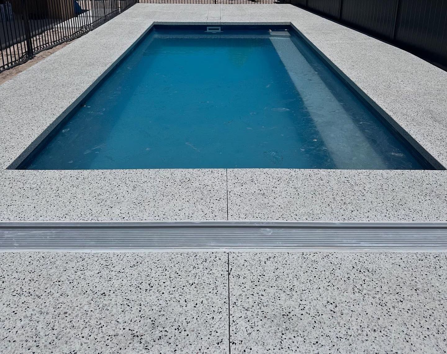 honed concrete pool surrounds with flush mounted skimmer box and water intake grate