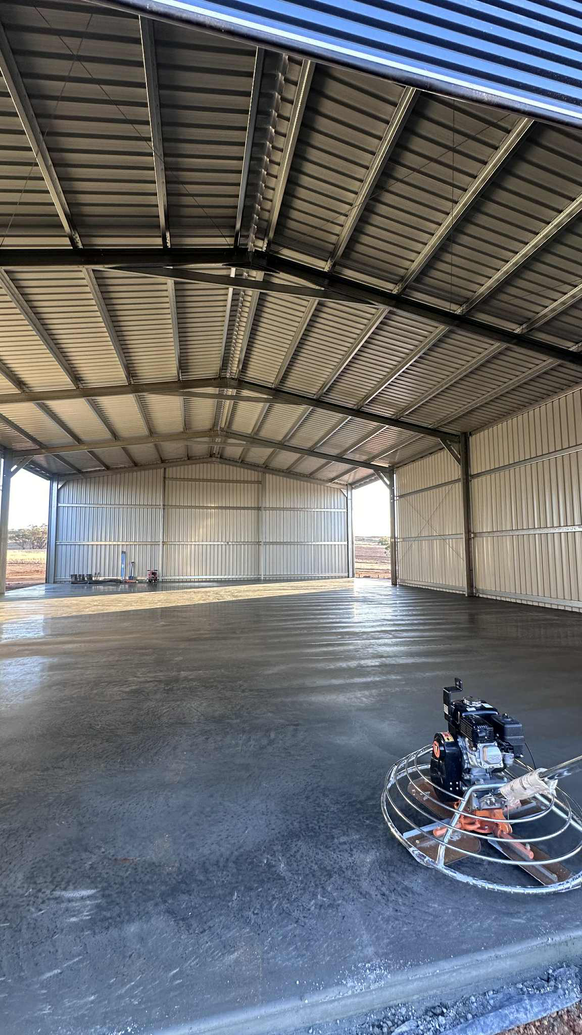 Large concrete shed pad in WA with trowel machine on the pad