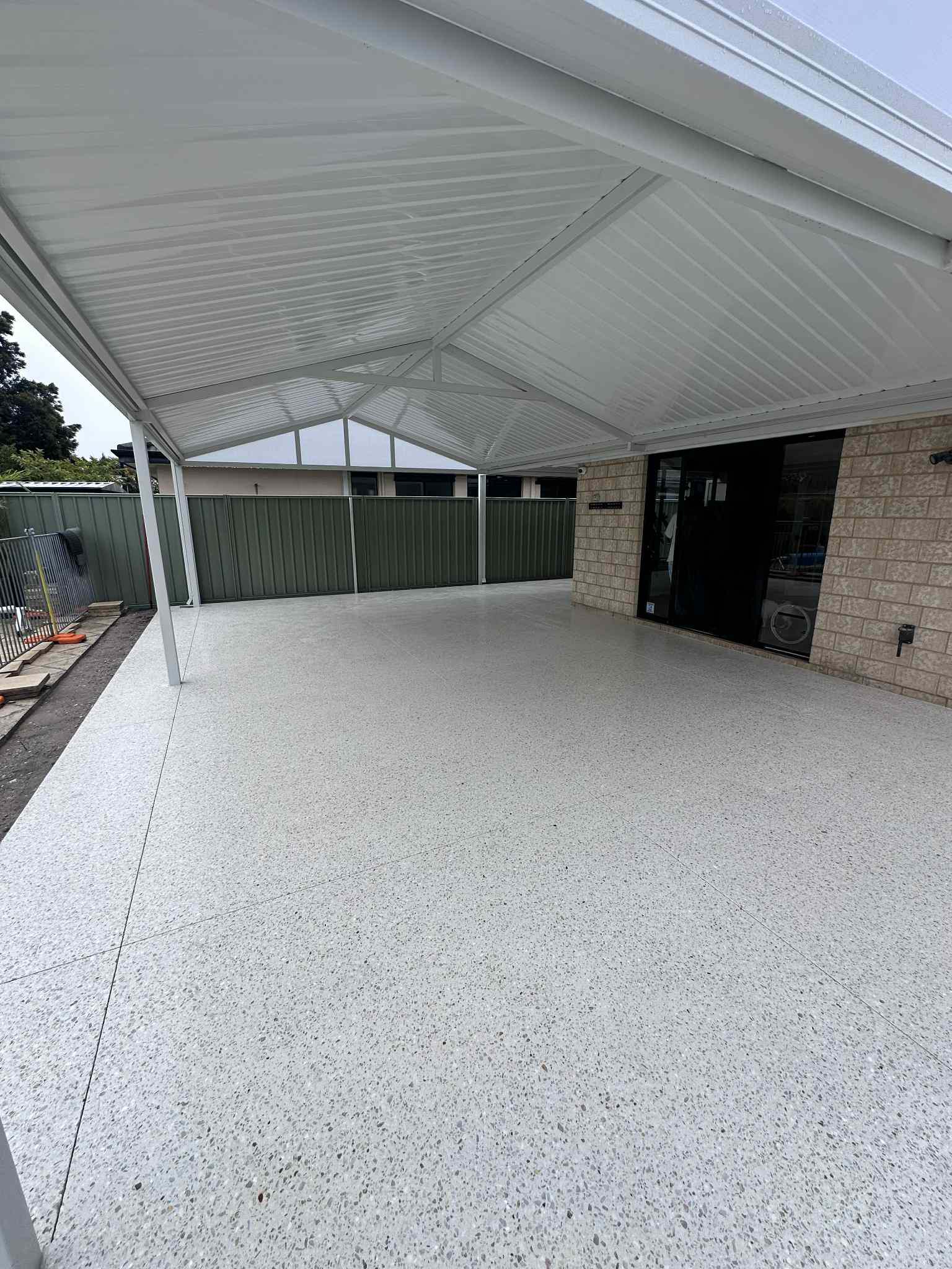 Honed concrete patio with patio roof over the top and house wall
