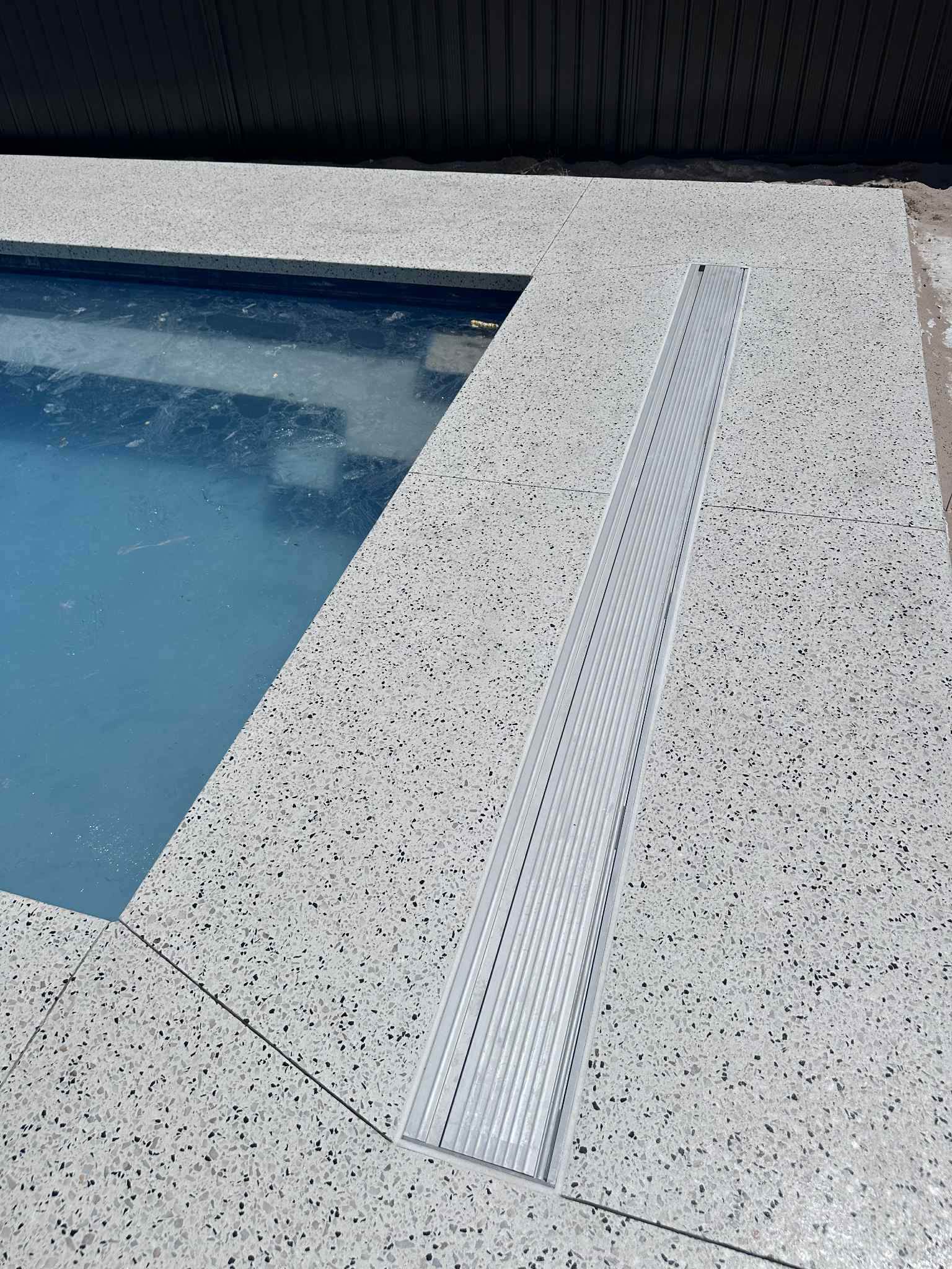 honed concrete pool surrounds with flush mounted skimmer box and water intake grate