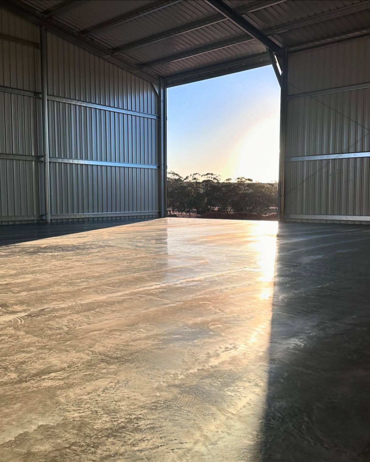 large shed with new concrete shed pad, amazing sunset and tin shed walls