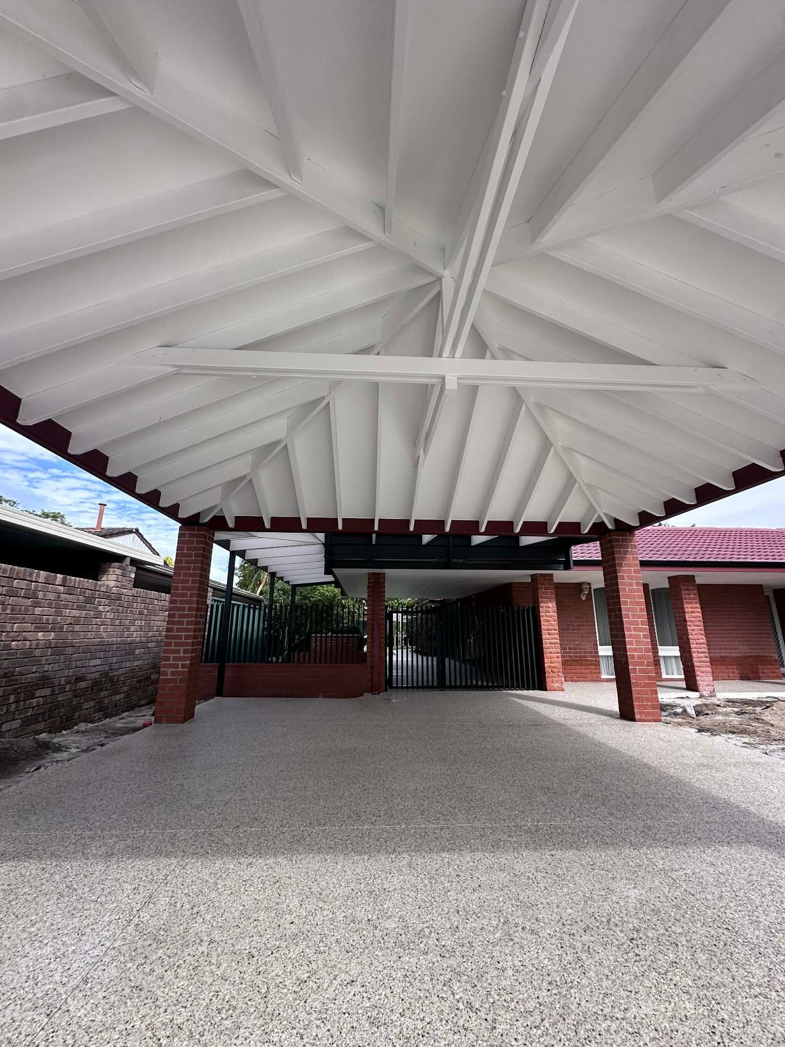 Covered outdoor entryway with white ceiling, brick supports, and gravel ground.