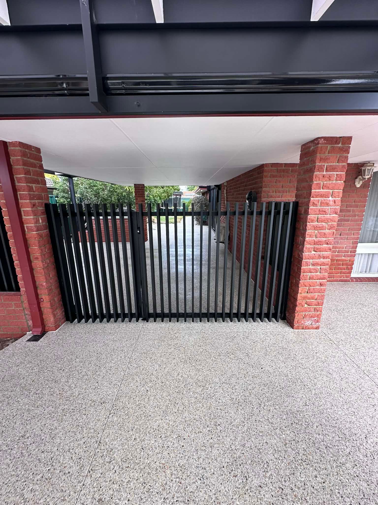 Exposed aggregate driveway and patio area with metal gate