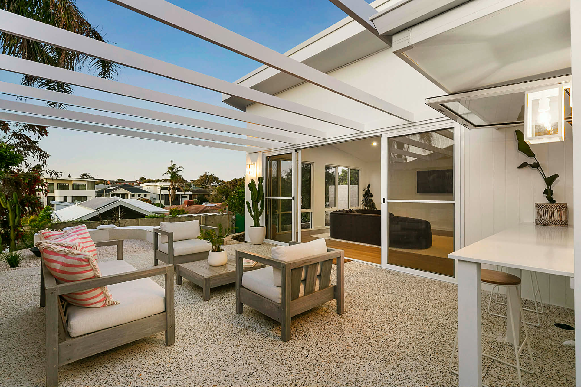 Wattle white exposed aggregate alfresco poured by Woodlands Construct with outdoor furniture and decor in North beach.