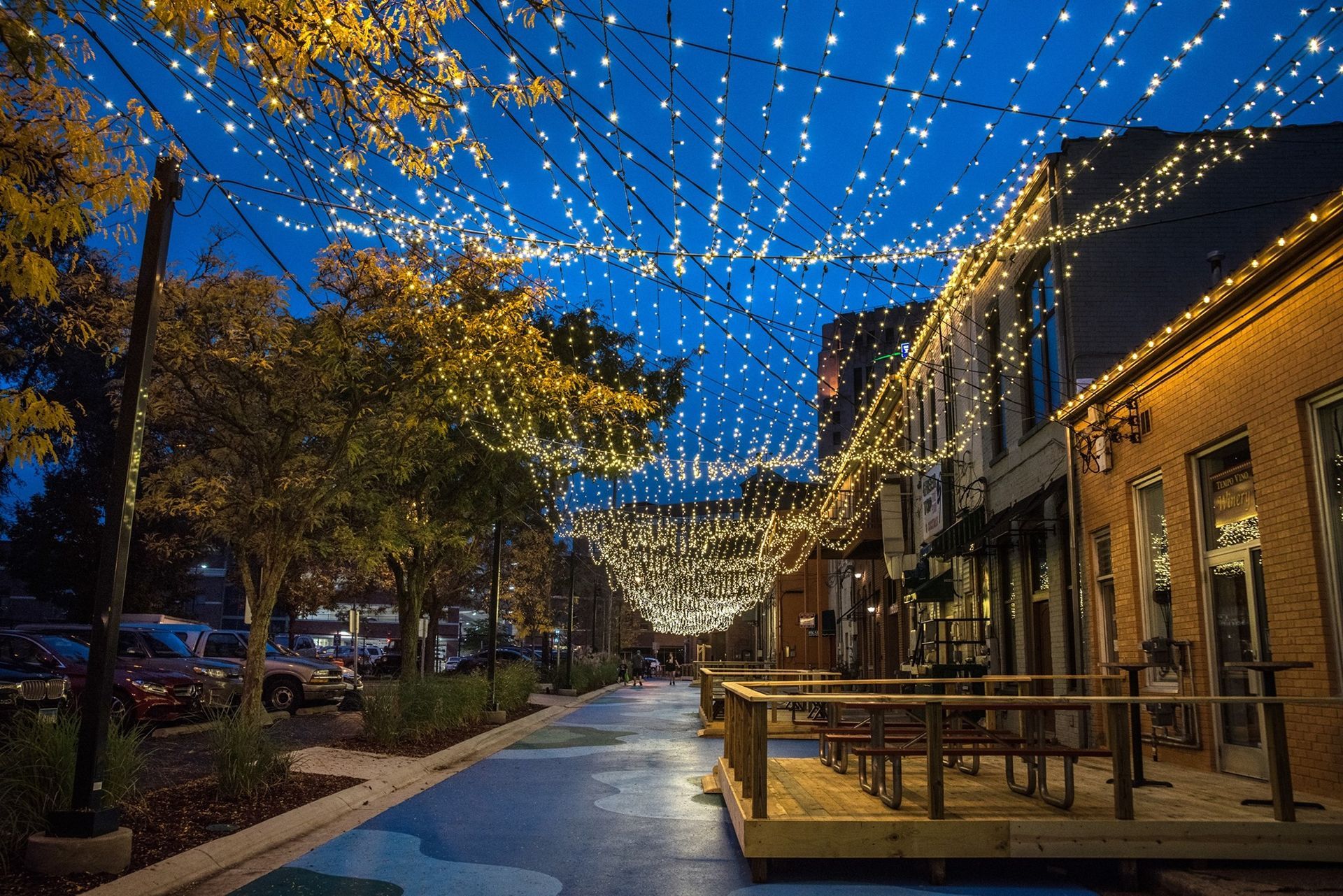 A row of buildings are lit up with string lights at night.