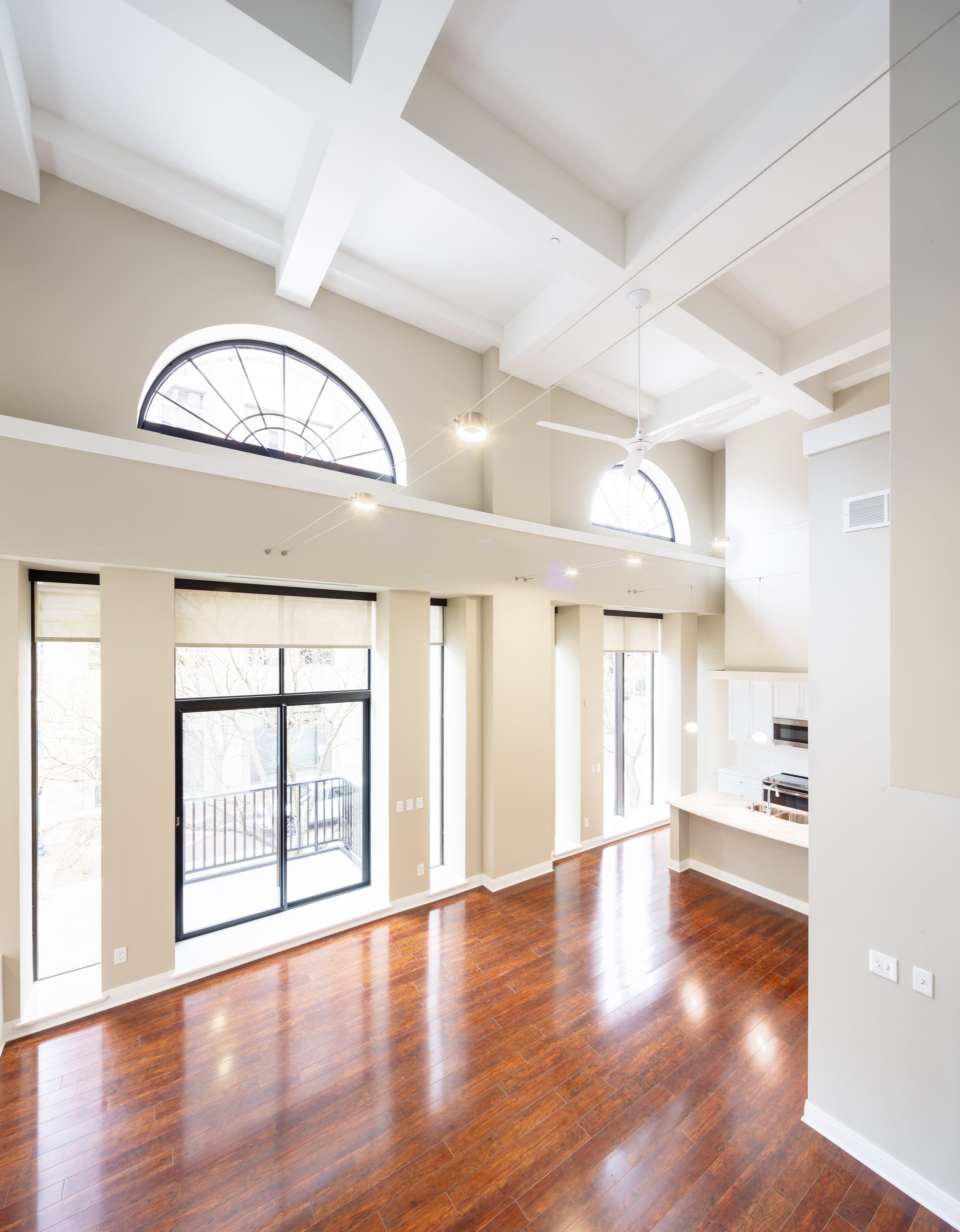 An empty living room with hardwood floors and lots of windows