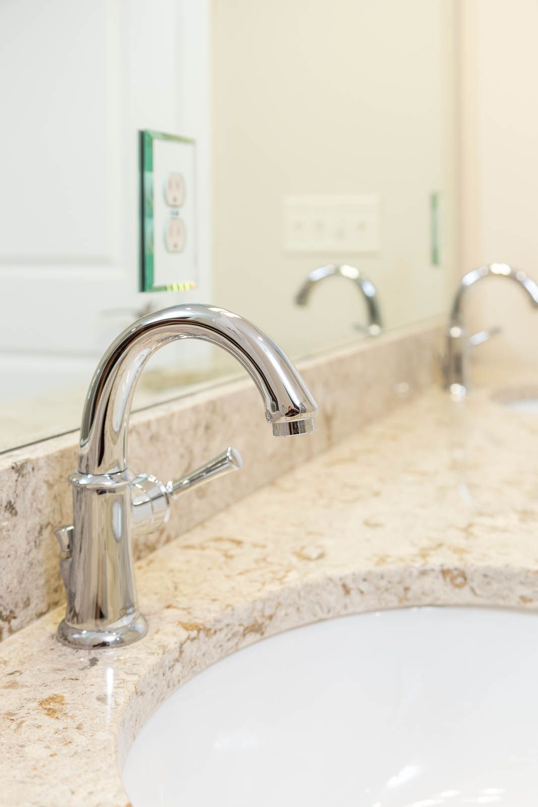 A bathroom sink with two faucets and a mirror.