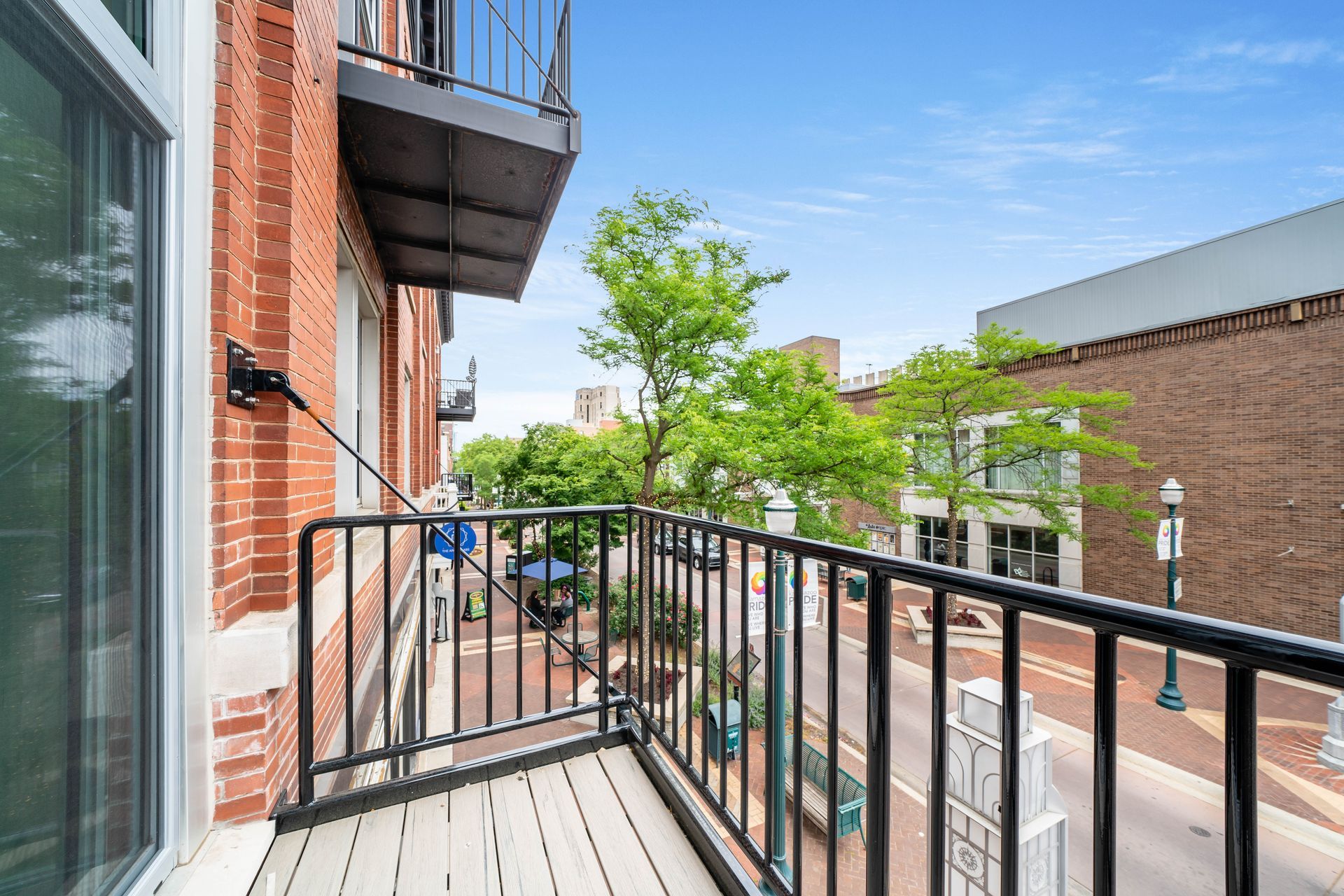 A balcony with a metal railing overlooking a city street.