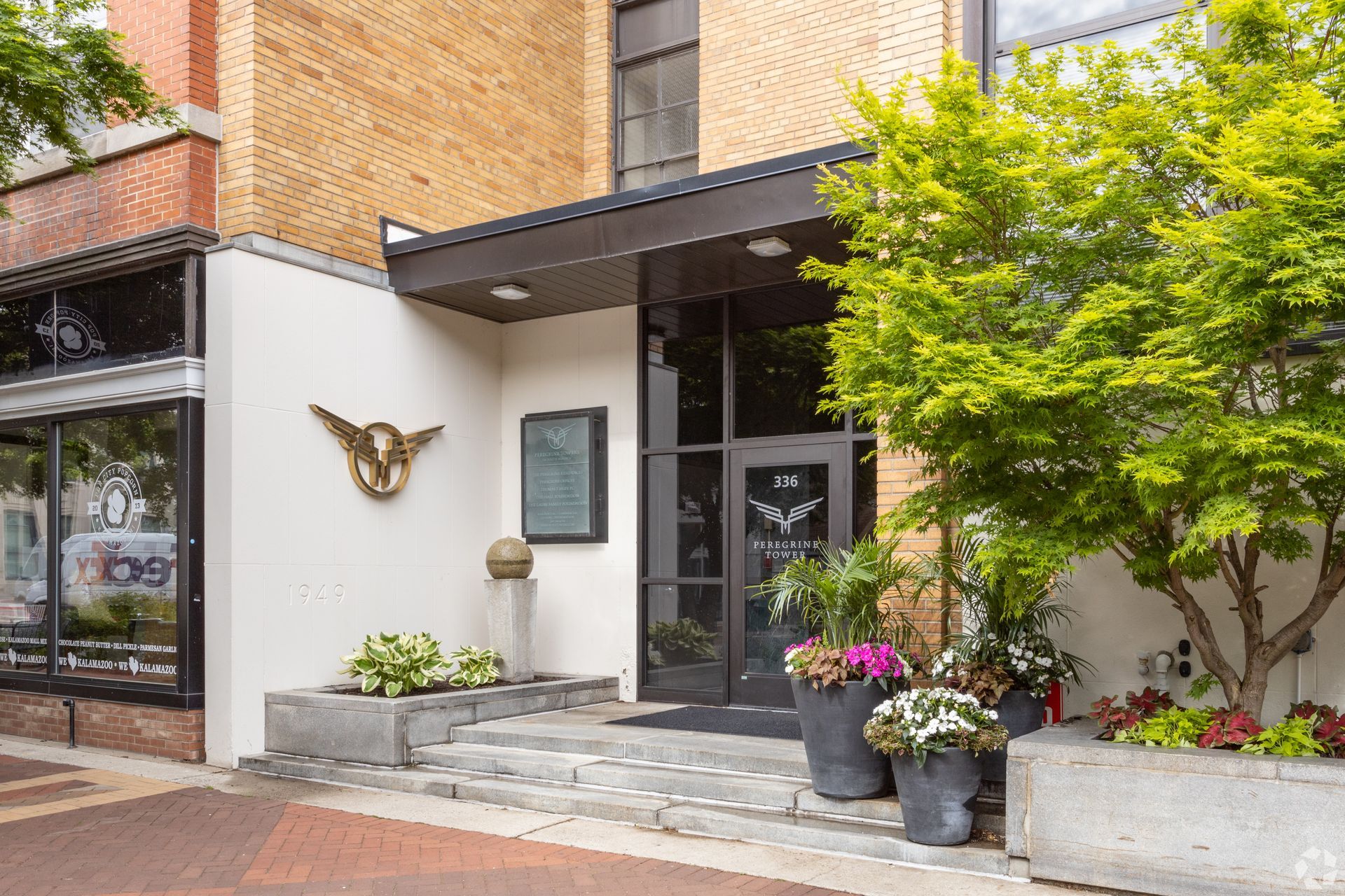The front entrance of a building with trees and flowers in front of it.