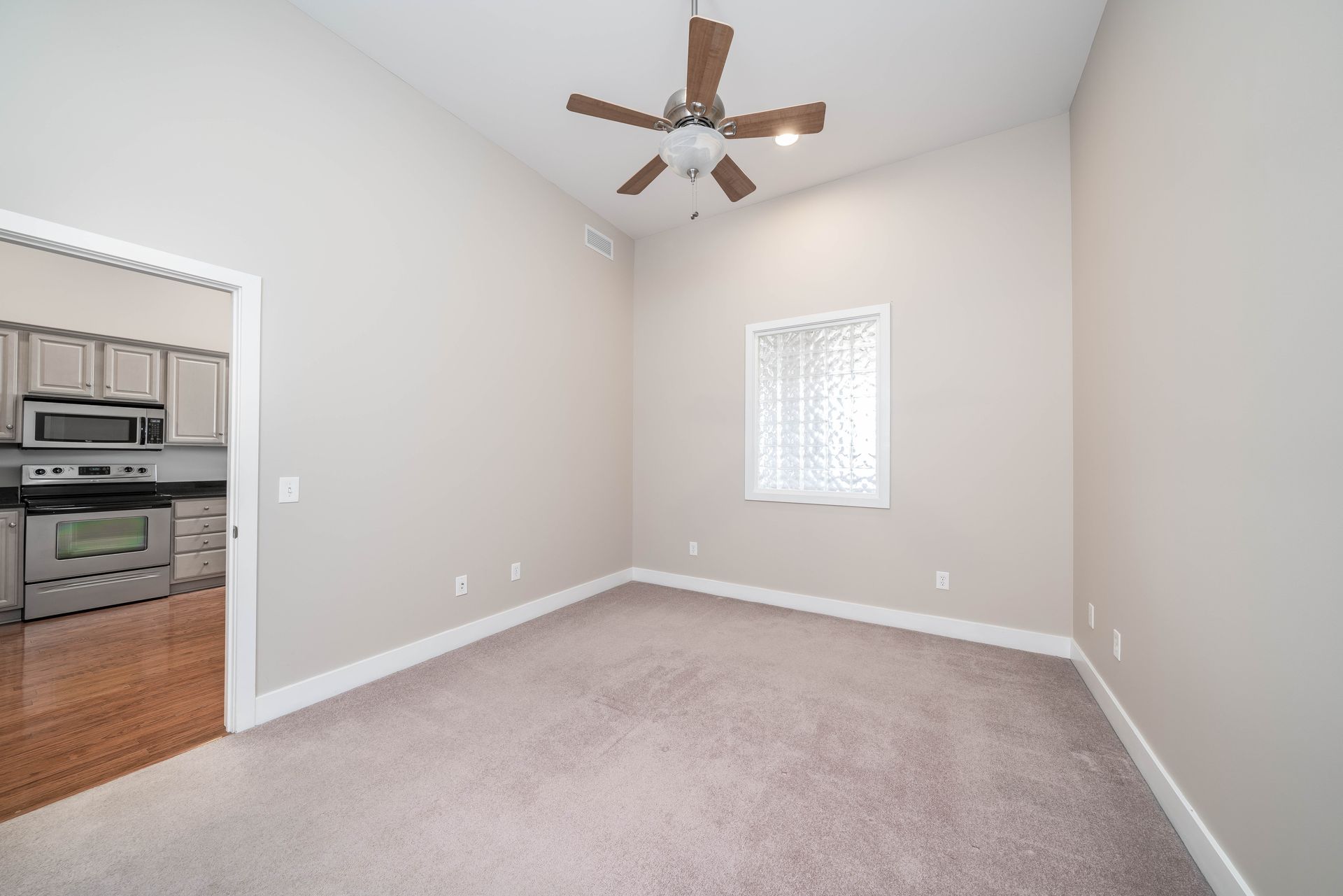 An empty room with a ceiling fan and a window.
