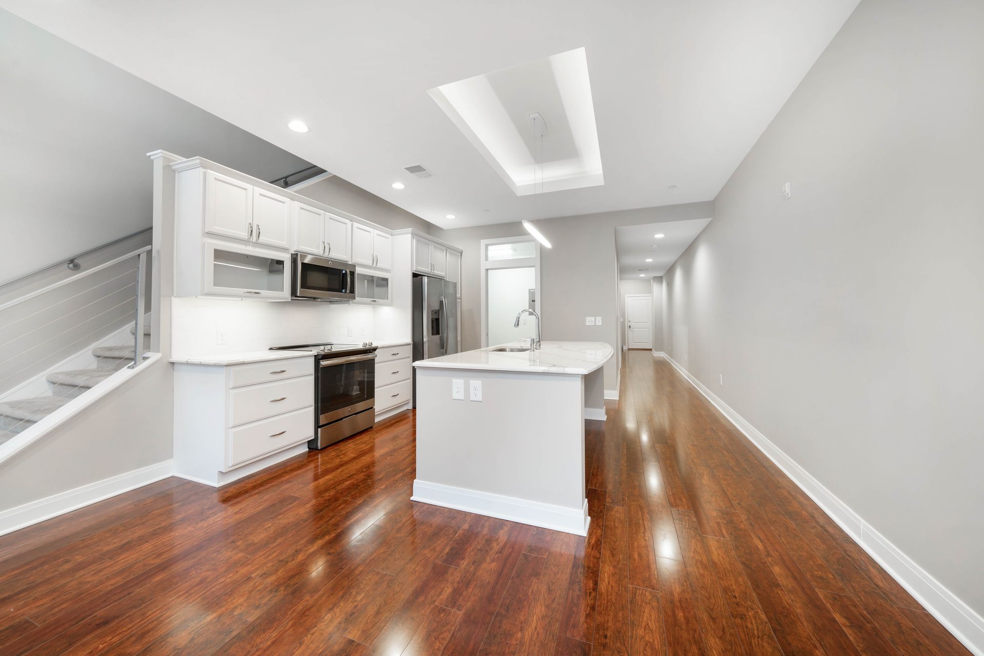 An empty kitchen with hardwood floors and white cabinets