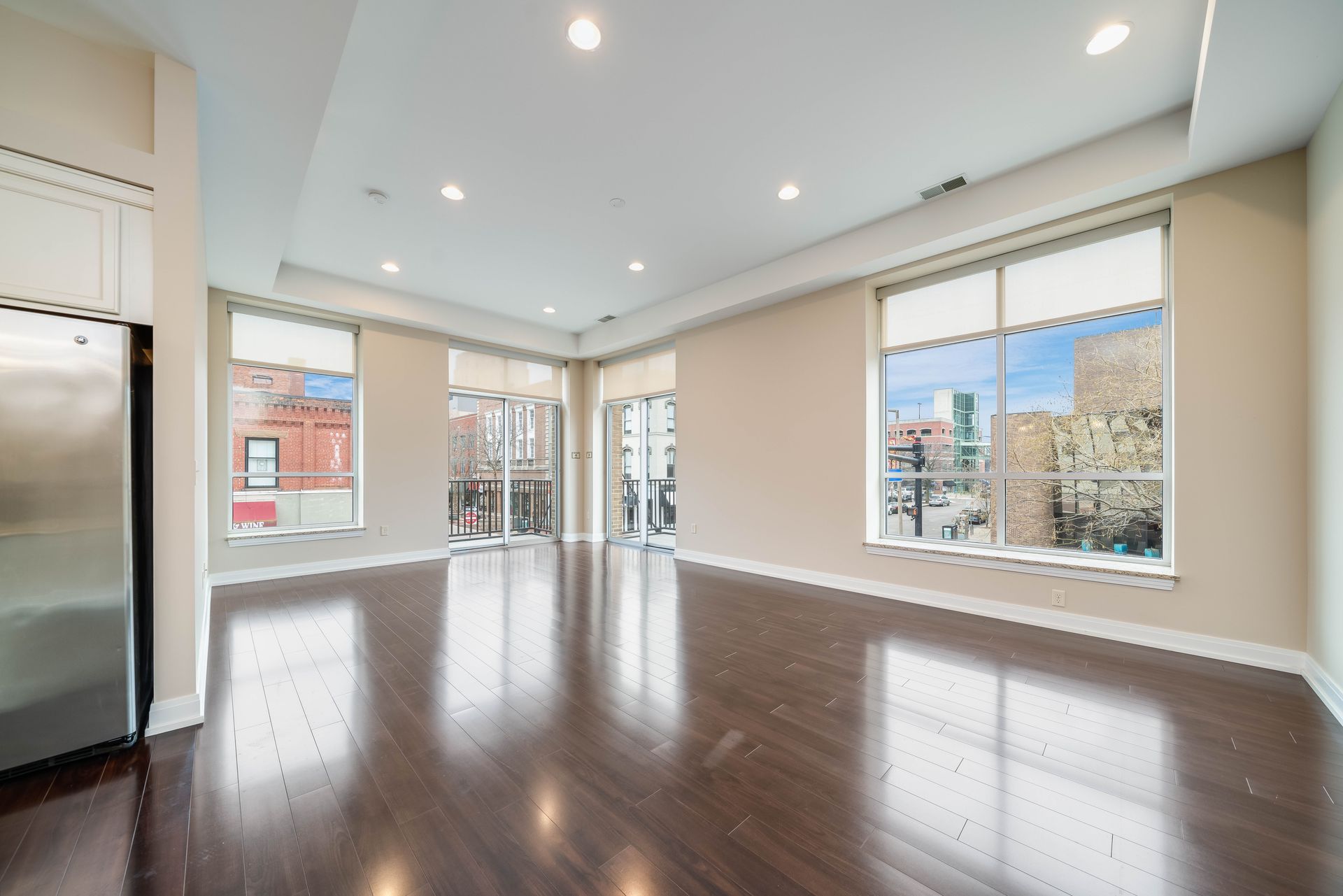 An empty living room with hardwood floors and lots of windows