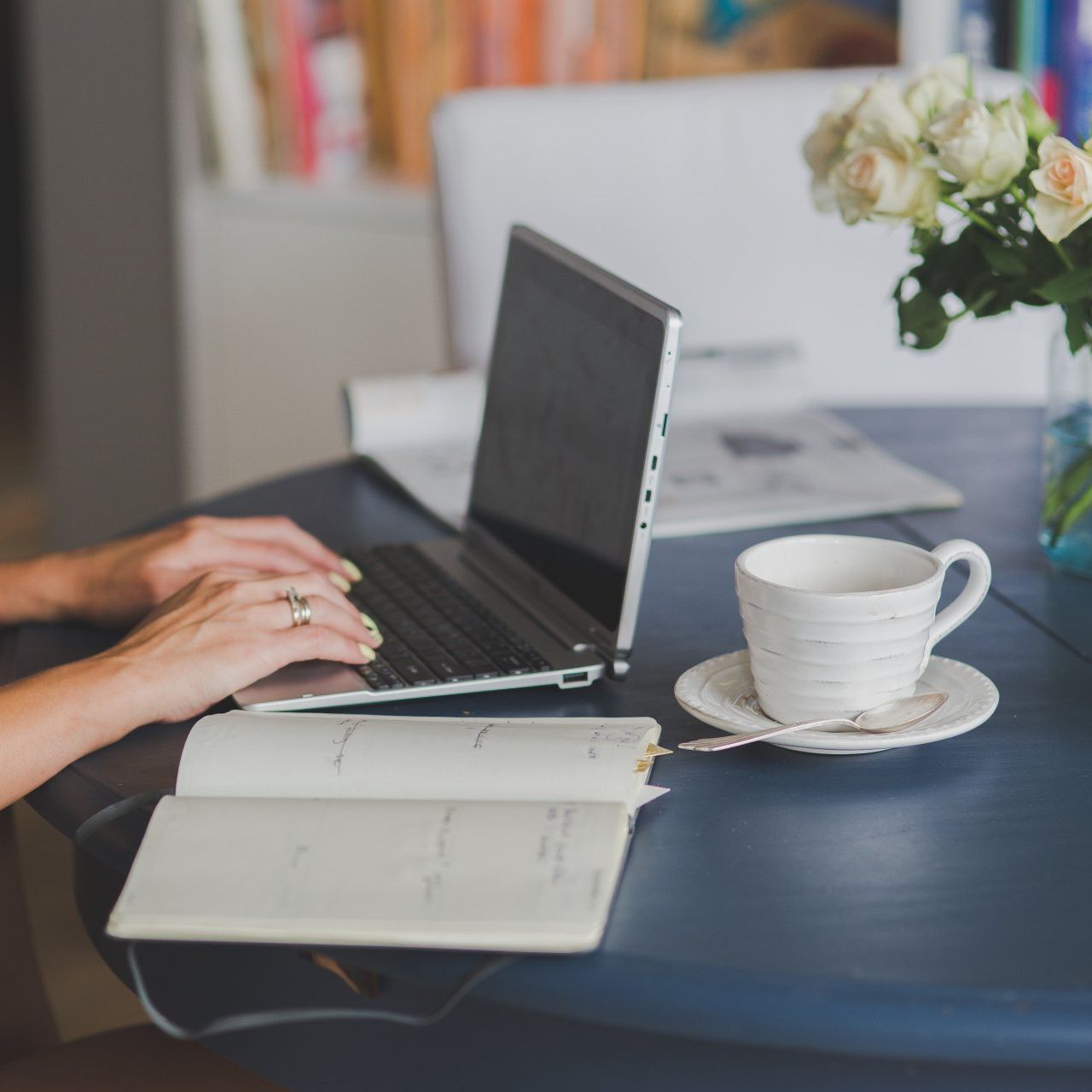 A person is typing on a laptop next to a cup of coffee