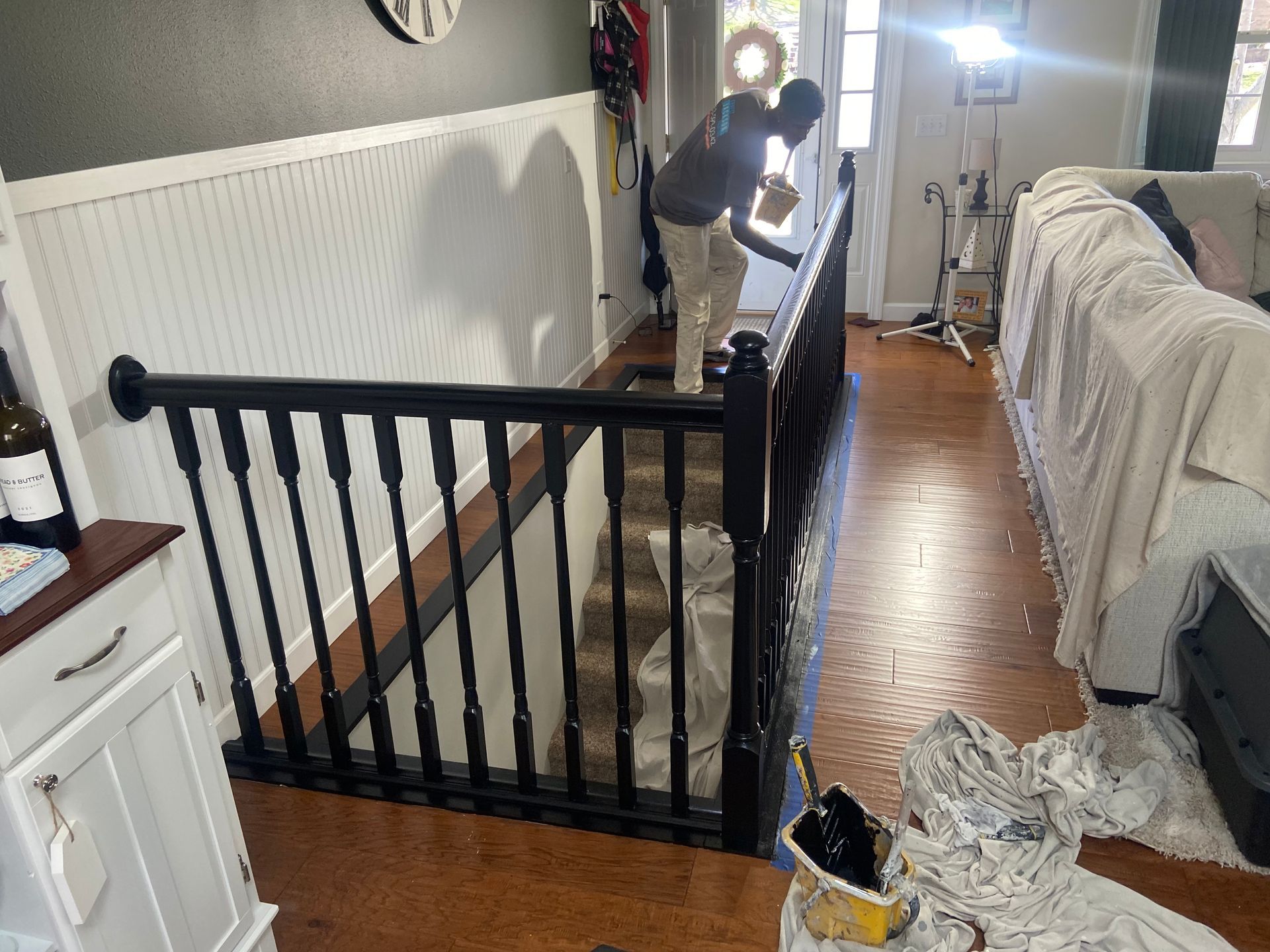 A man is painting a railing in a living room.