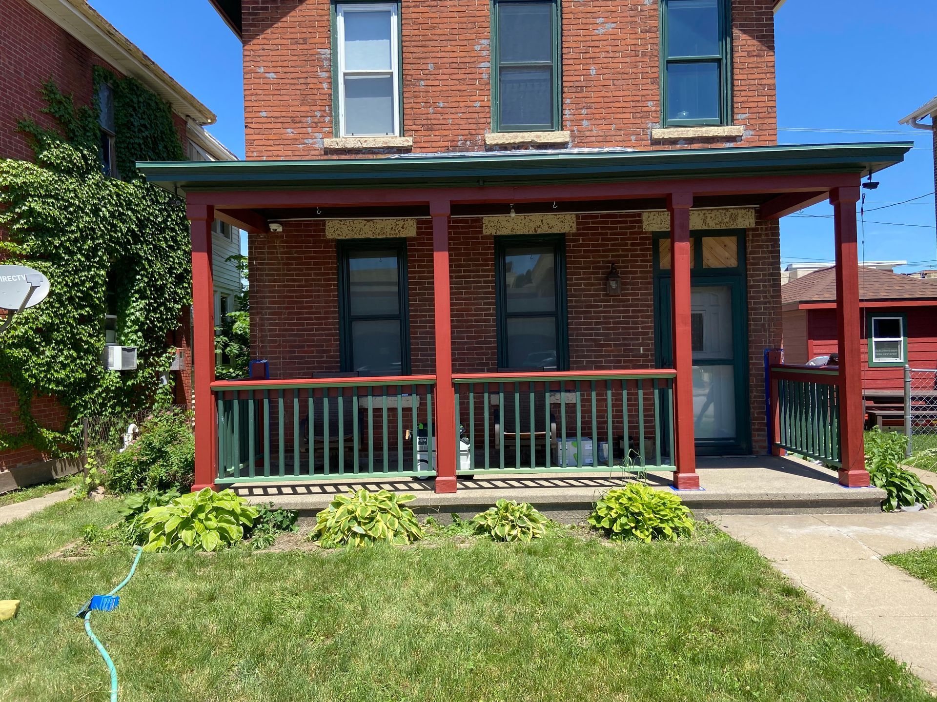 A brick house with a porch and a hose in front of it