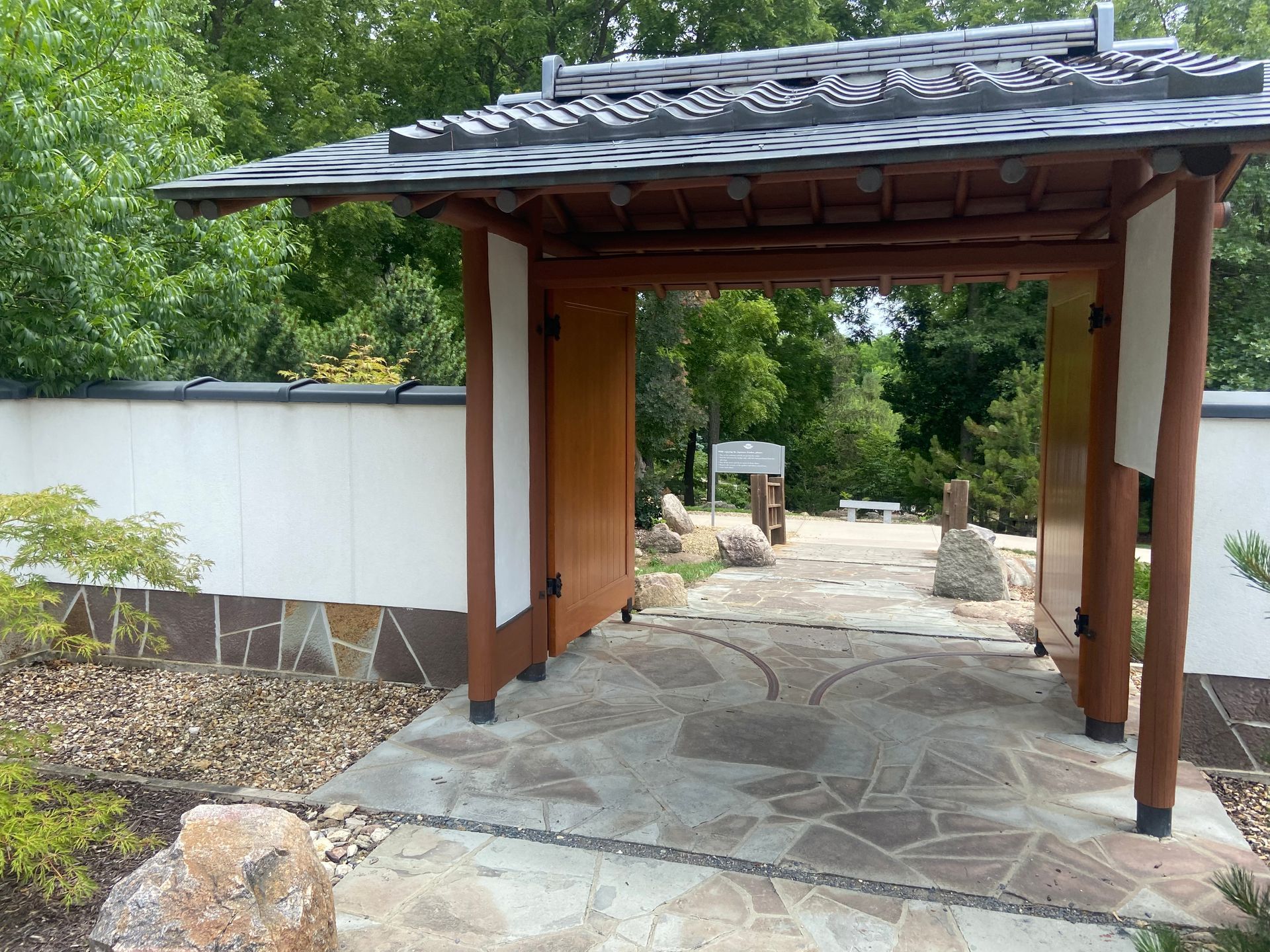 A wooden gate leading to a garden with trees in the background